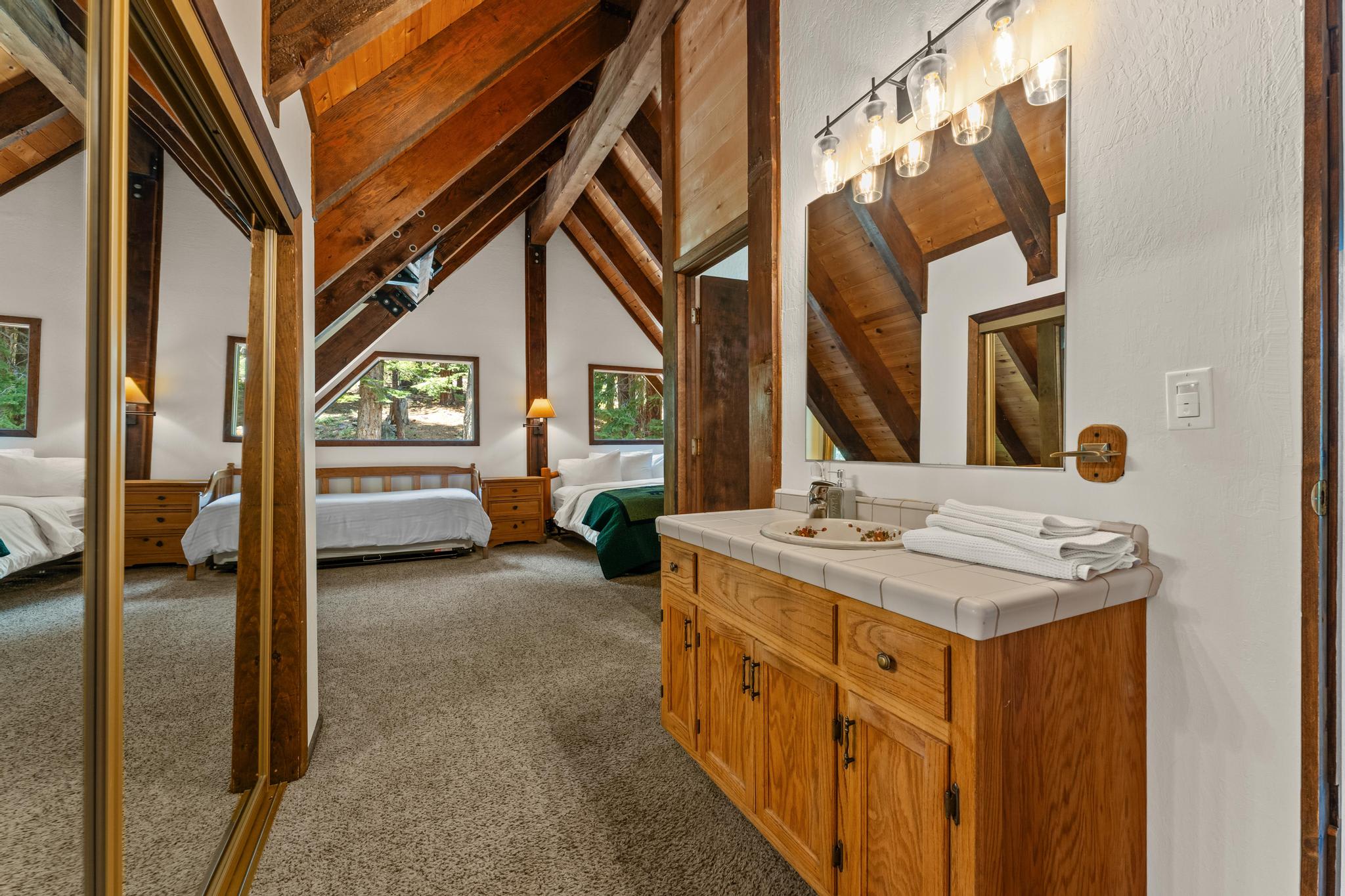 Cozy Tahoe Vista vacation rental with wood interiors, bathroom, and bedroom, featuring sloped ceilings and forest views.