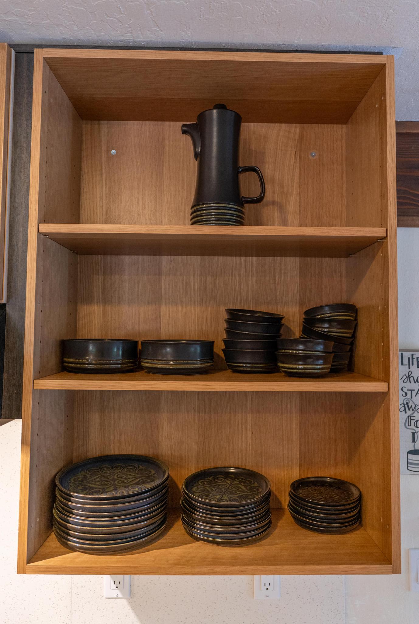 Open kitchen cabinet in Tahoe Vista vacation rental with sleek black dishware neatly stacked inside.