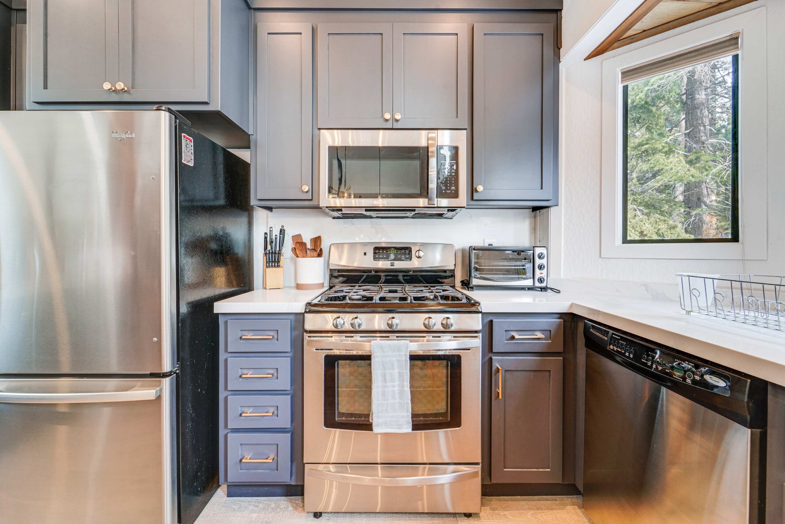 Modern kitchen in a Truckee vacation rental with stainless steel appliances and a view of trees through the window.