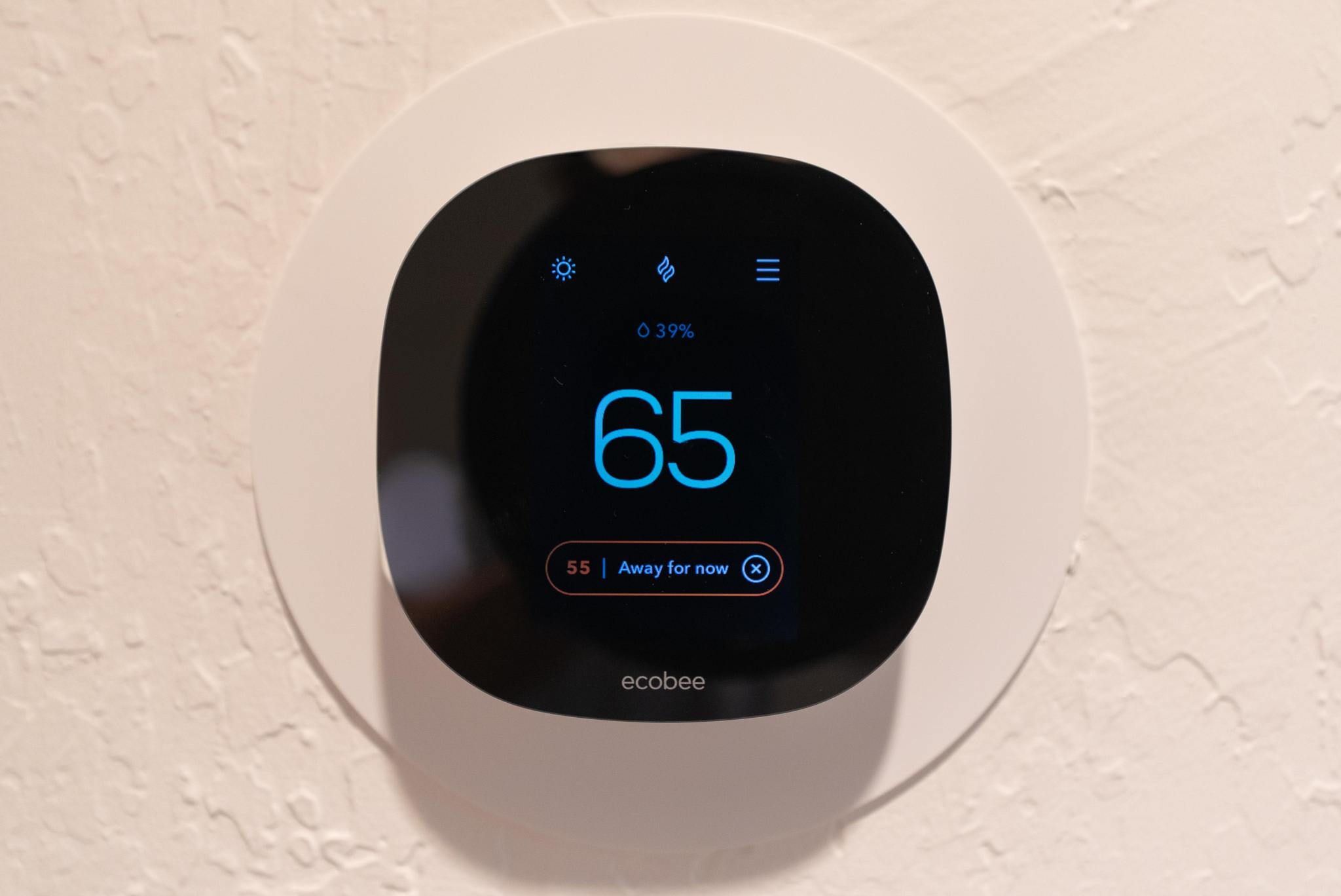 Smart thermostat set to 65 in a Truckee vacation rental, mounted on a textured wall.