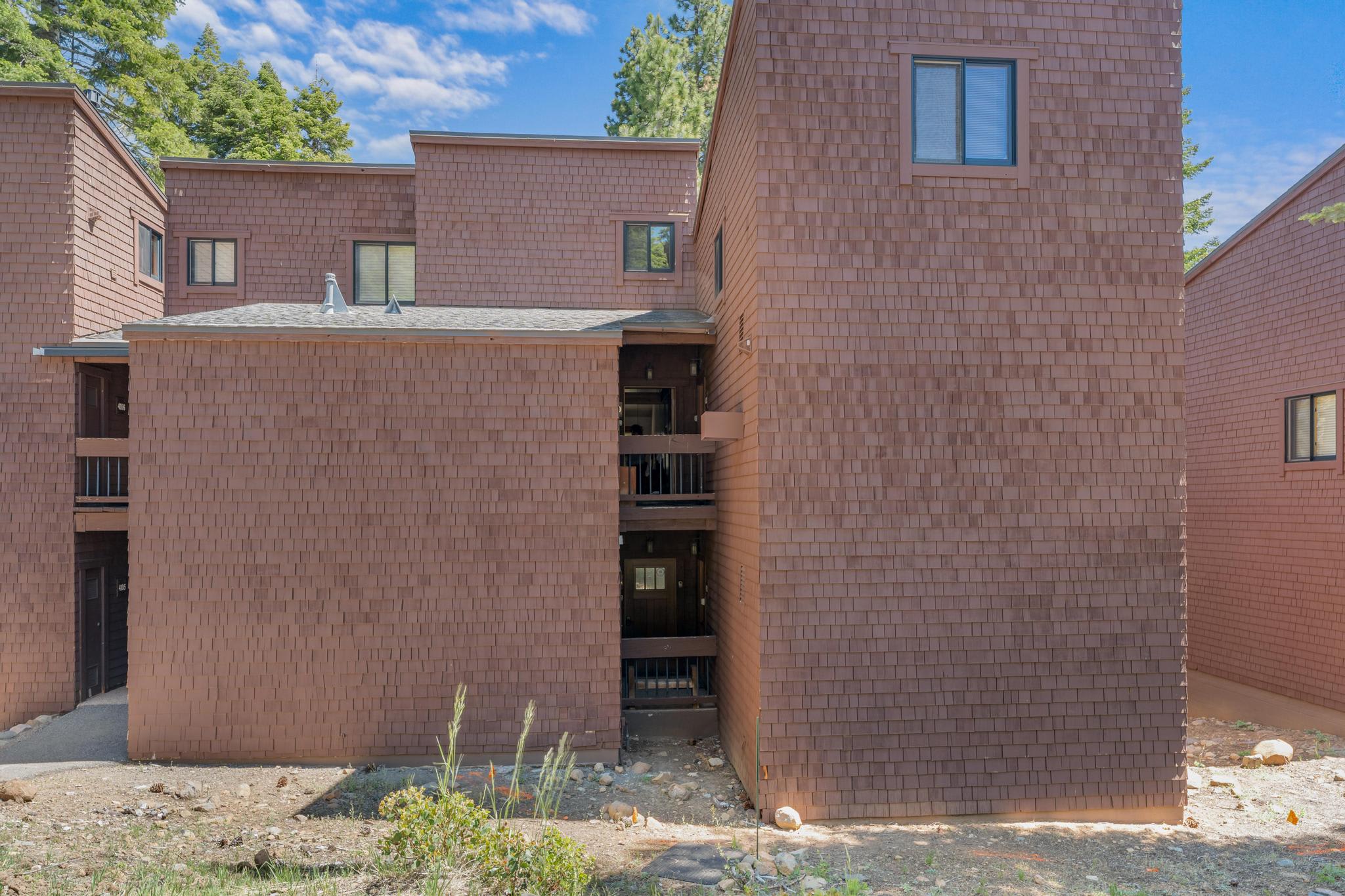 Brown wood-paneled vacation rental in Truckee with multiple stories, surrounded by trees under a blue sky.