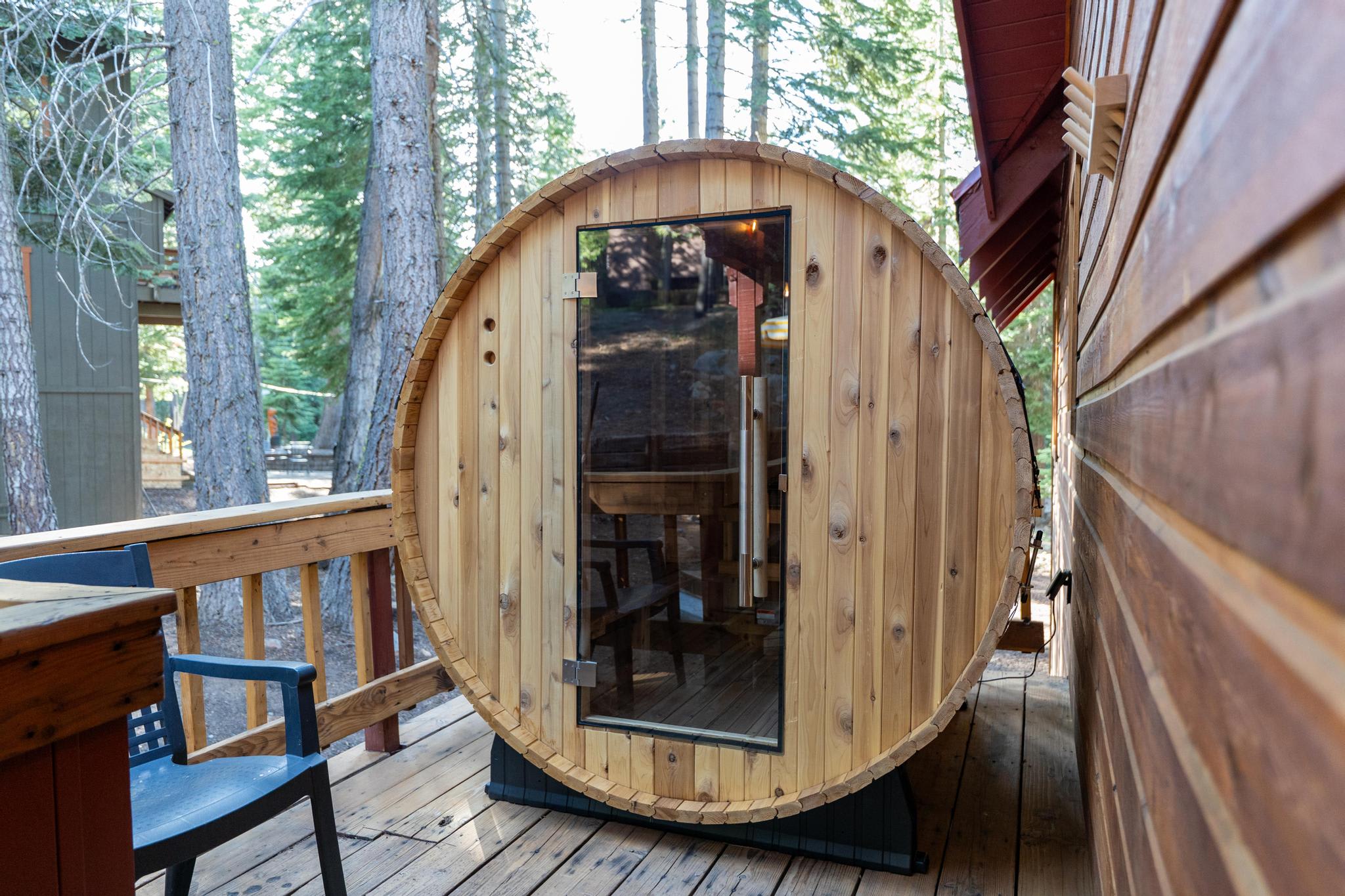 Wooden barrel sauna on a deck at a vacation rental in Tahoe Vista, surrounded by tall trees.