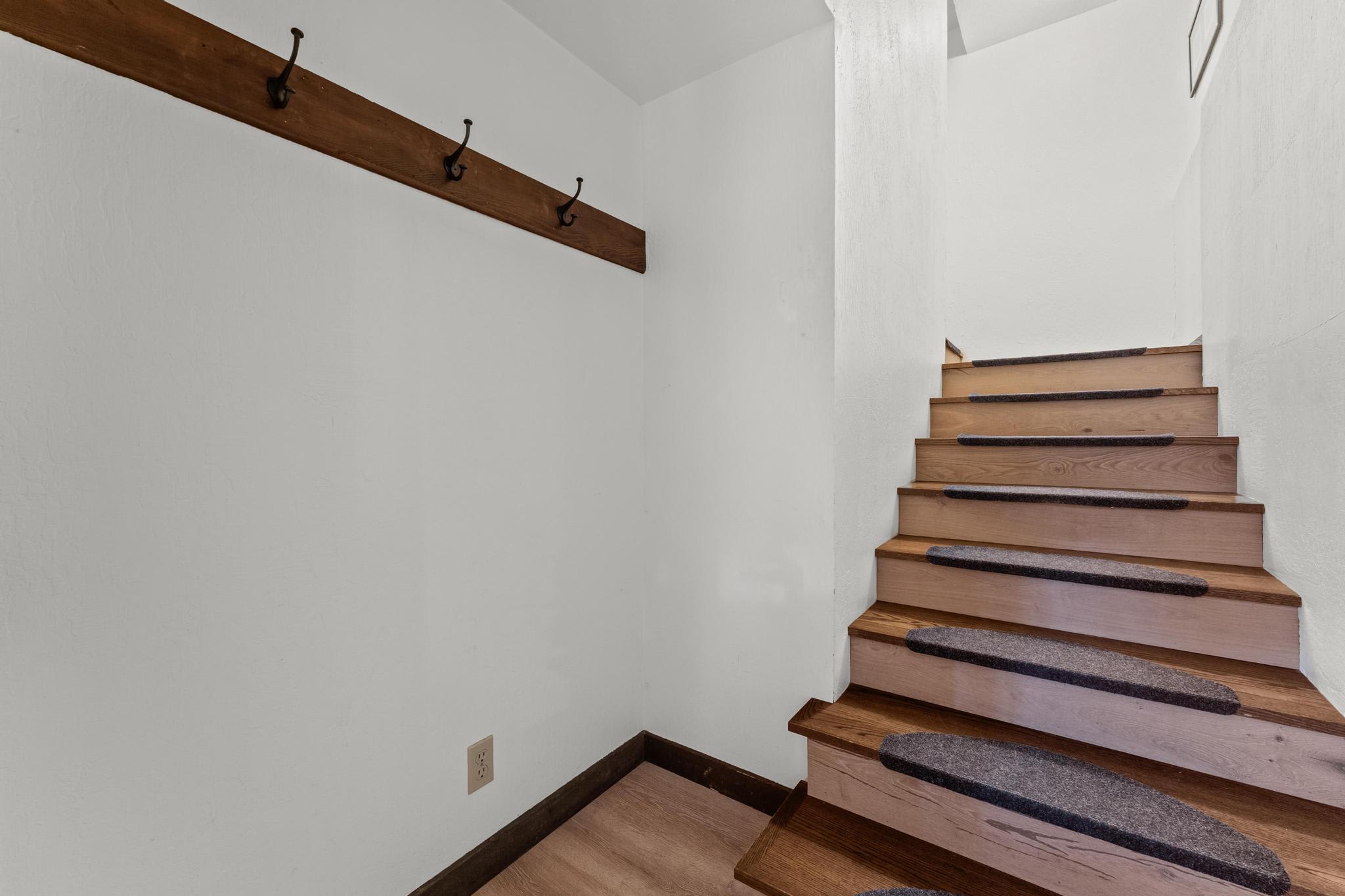 Wooden staircase in a Tahoe Vista vacation rental, featuring coat hooks and white walls.