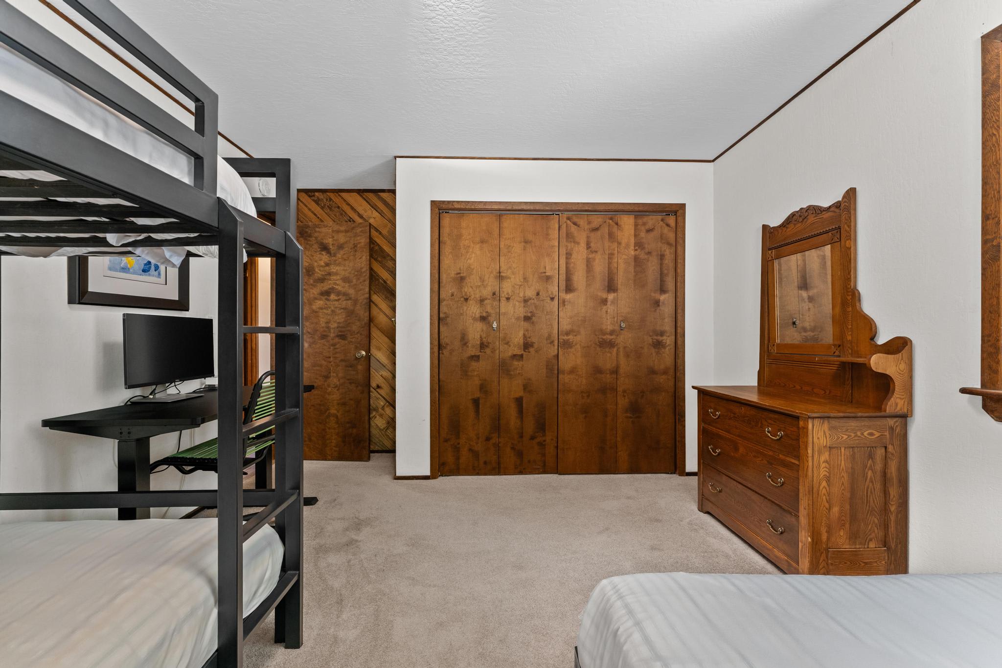 Bedroom in a Tahoe Vista vacation rental with bunk bed, desk, and wooden dresser, featuring a rustic design.