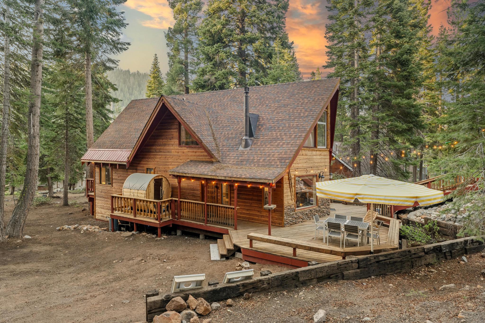 Cozy wooden cabin vacation rental in Tahoe Vista, surrounded by tall trees, featuring a deck with outdoor seating.