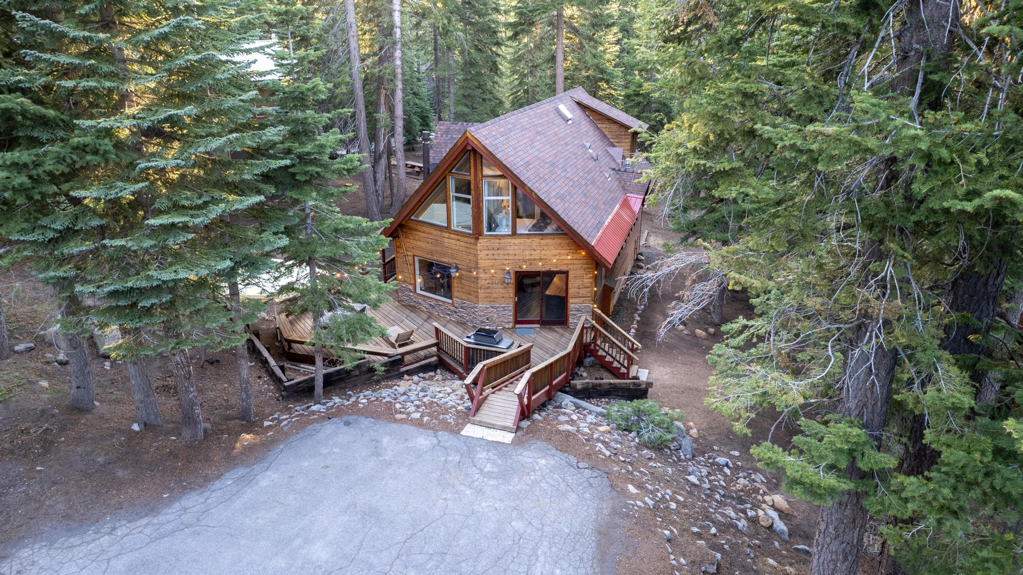 A-frame vacation rental nestled in a forest setting in Tahoe Vista, showcasing a rustic wooden exterior and wraparound deck.