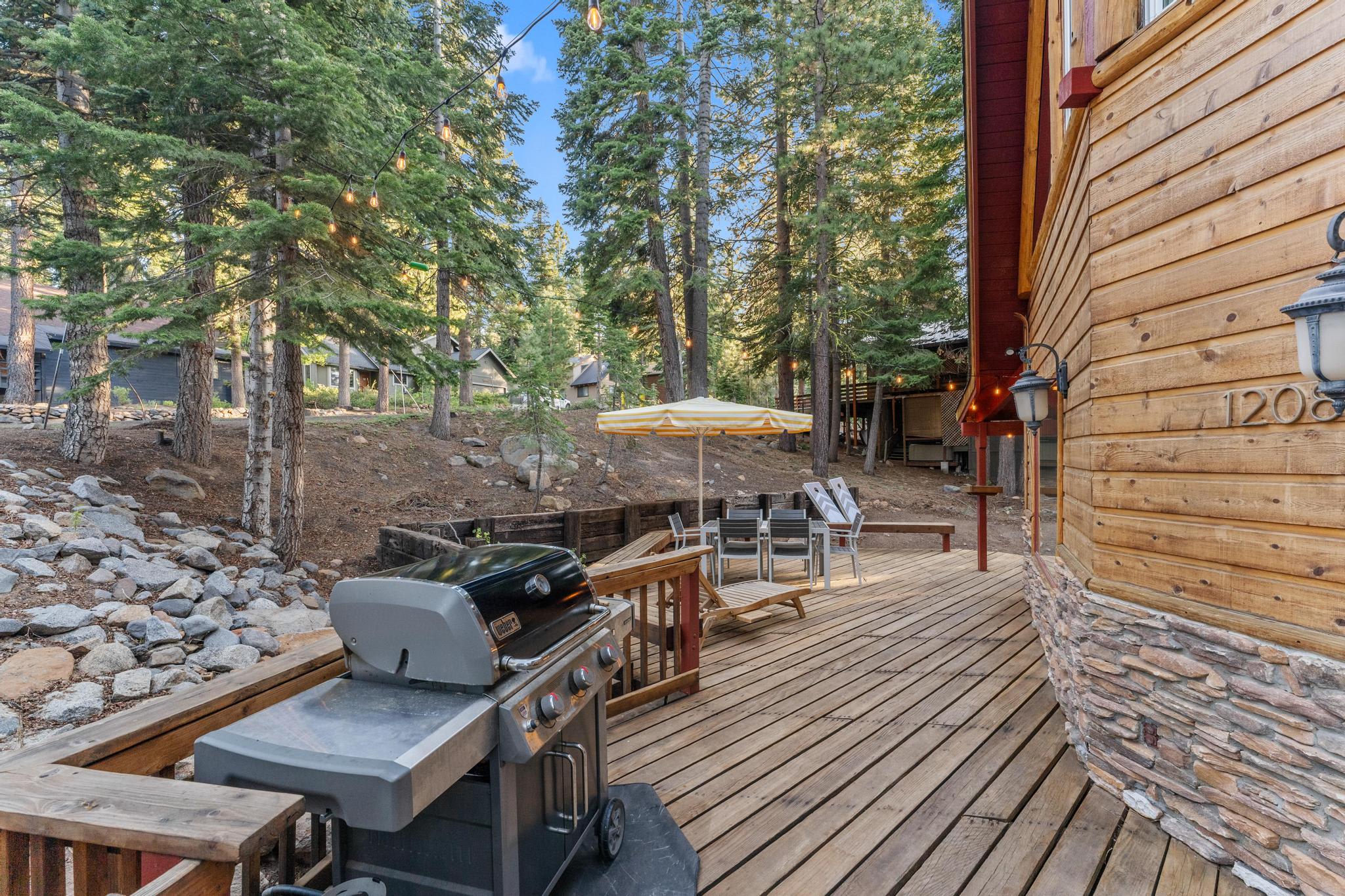 Deck with grill and seating at a Tahoe Vista vacation rental, surrounded by trees and a peaceful forest setting.