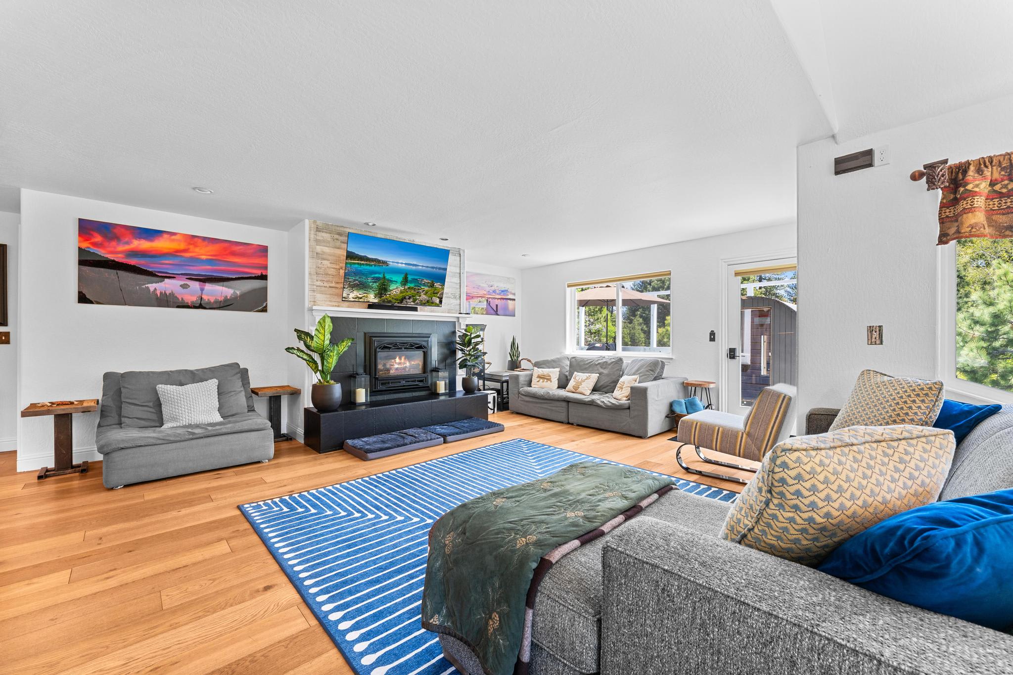 Spacious living room in a Truckee vacation rental, featuring cozy sofas, a fireplace, and large windows with natural light.