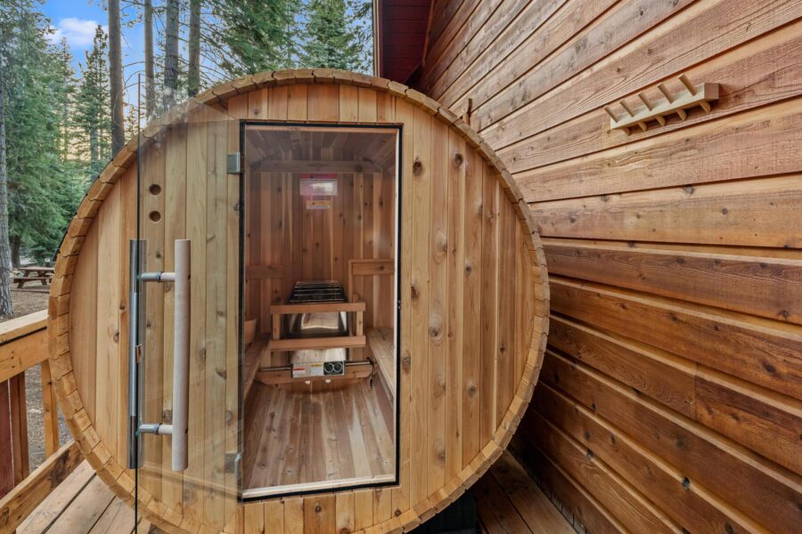 Barrel sauna on the deck of a Tahoe Vista vacation rental, surrounded by tall pine trees.