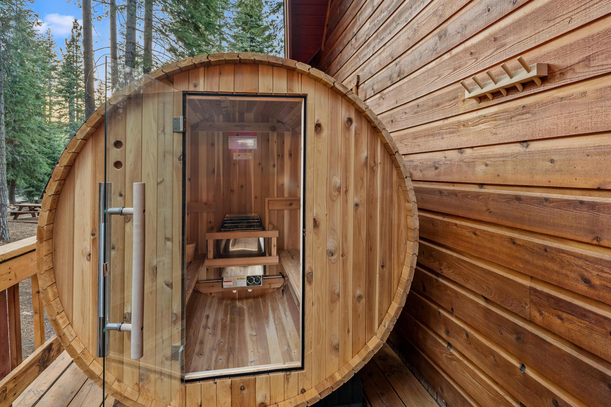 Barrel sauna on the deck of a Tahoe Vista vacation rental, surrounded by tall pine trees.