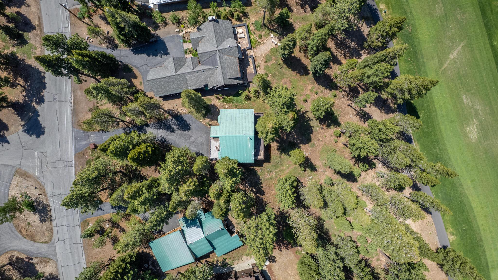 Aerial view of vacation rental homes among trees in Truckee, next to a road and golf course.