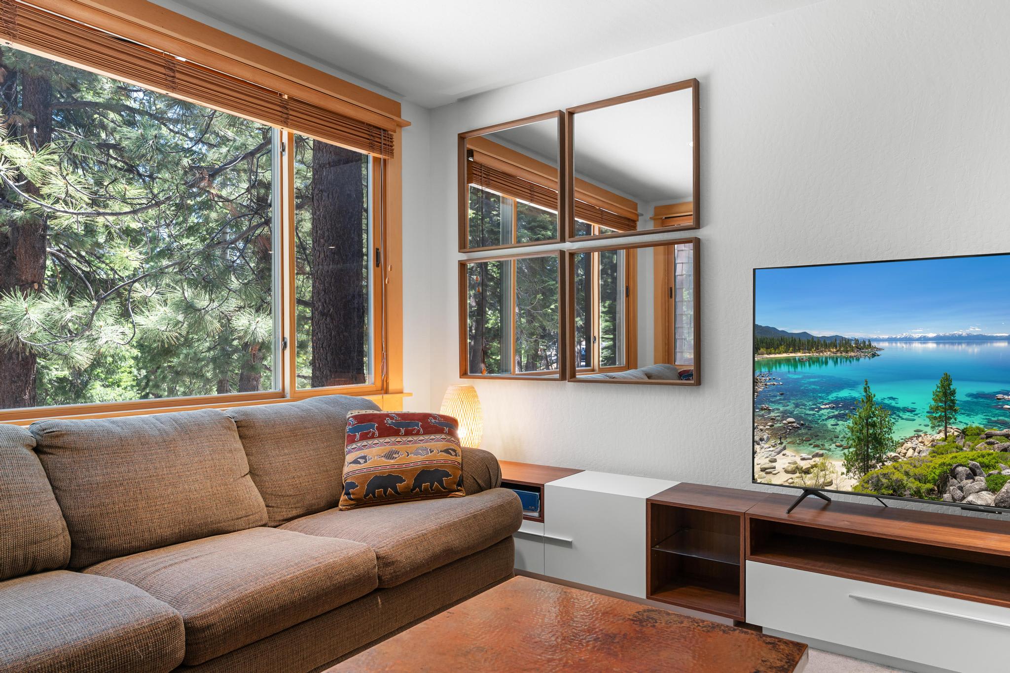 Cozy living room in Truckee vacation rental, featuring a large window with forest views and a flat-screen TV.