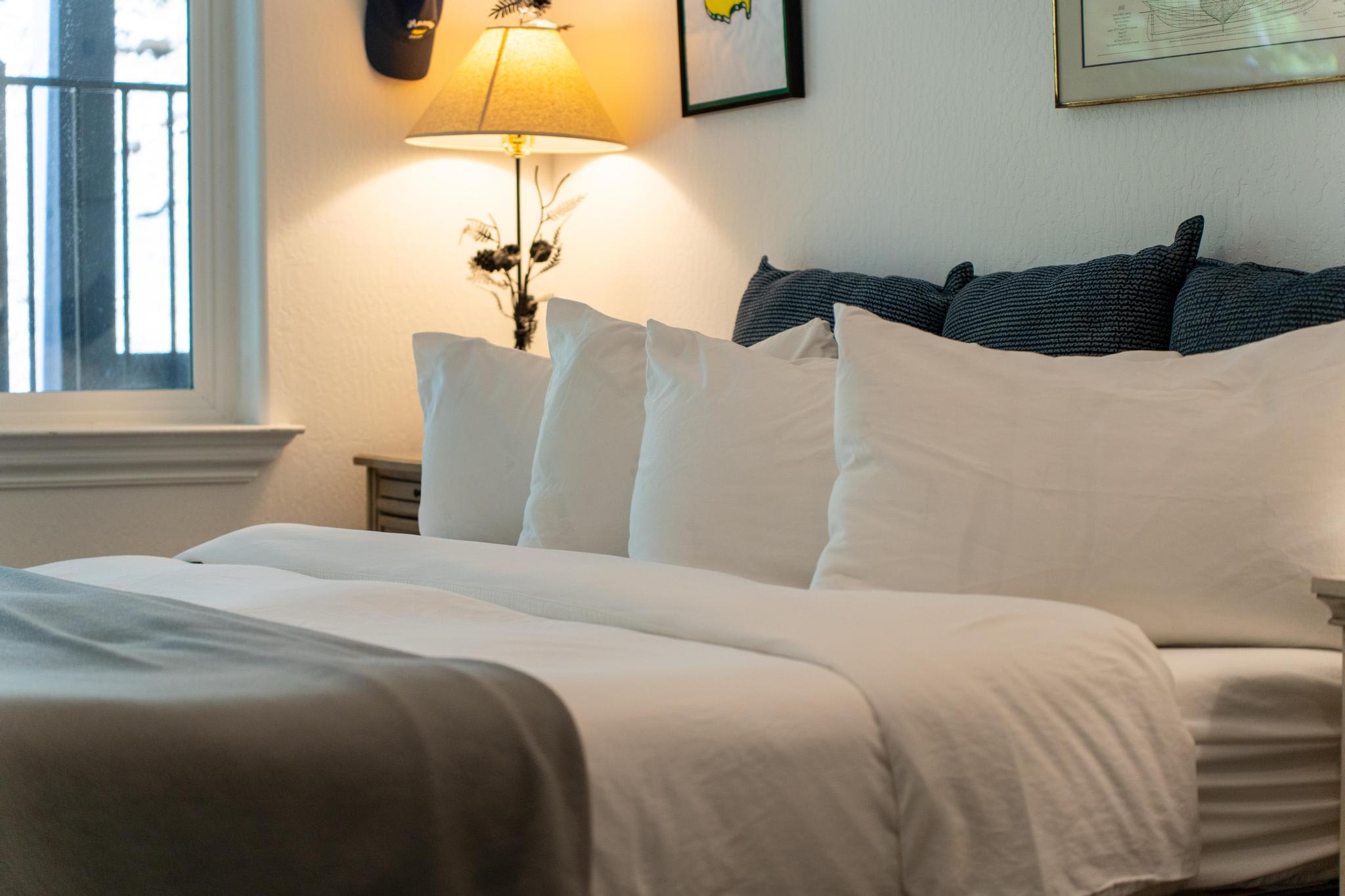 Cozy bedroom in a Truckee vacation rental featuring a neatly made bed with plush white pillows and warm lighting.