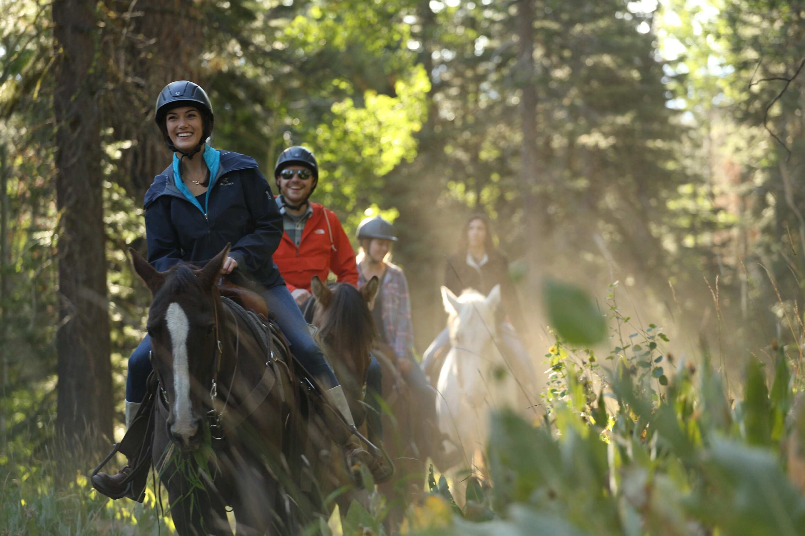 People horseback riding through forest near Truckee, enjoying nature close to a vacation rental.