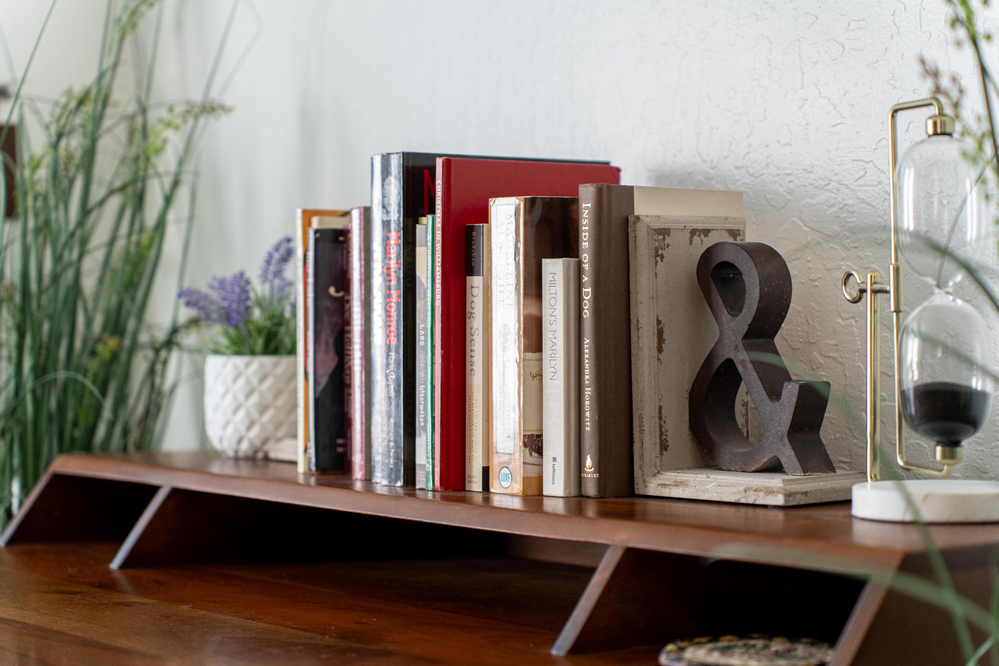 Books and decor on a wooden shelf in a Truckee vacation rental, featuring a plant and an hourglass.