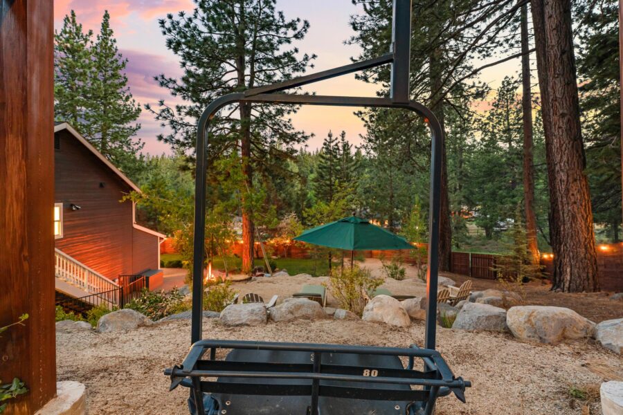 Scenic backyard view of a Truckee vacation rental, featuring trees, a green umbrella, and sunset skies.