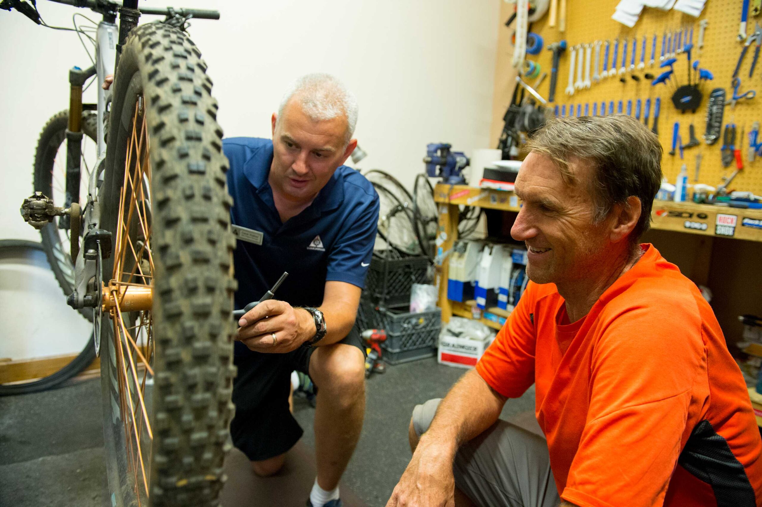 Two men in a workshop fixing a bike, ideal activity near a vacation rental in Truckee.
