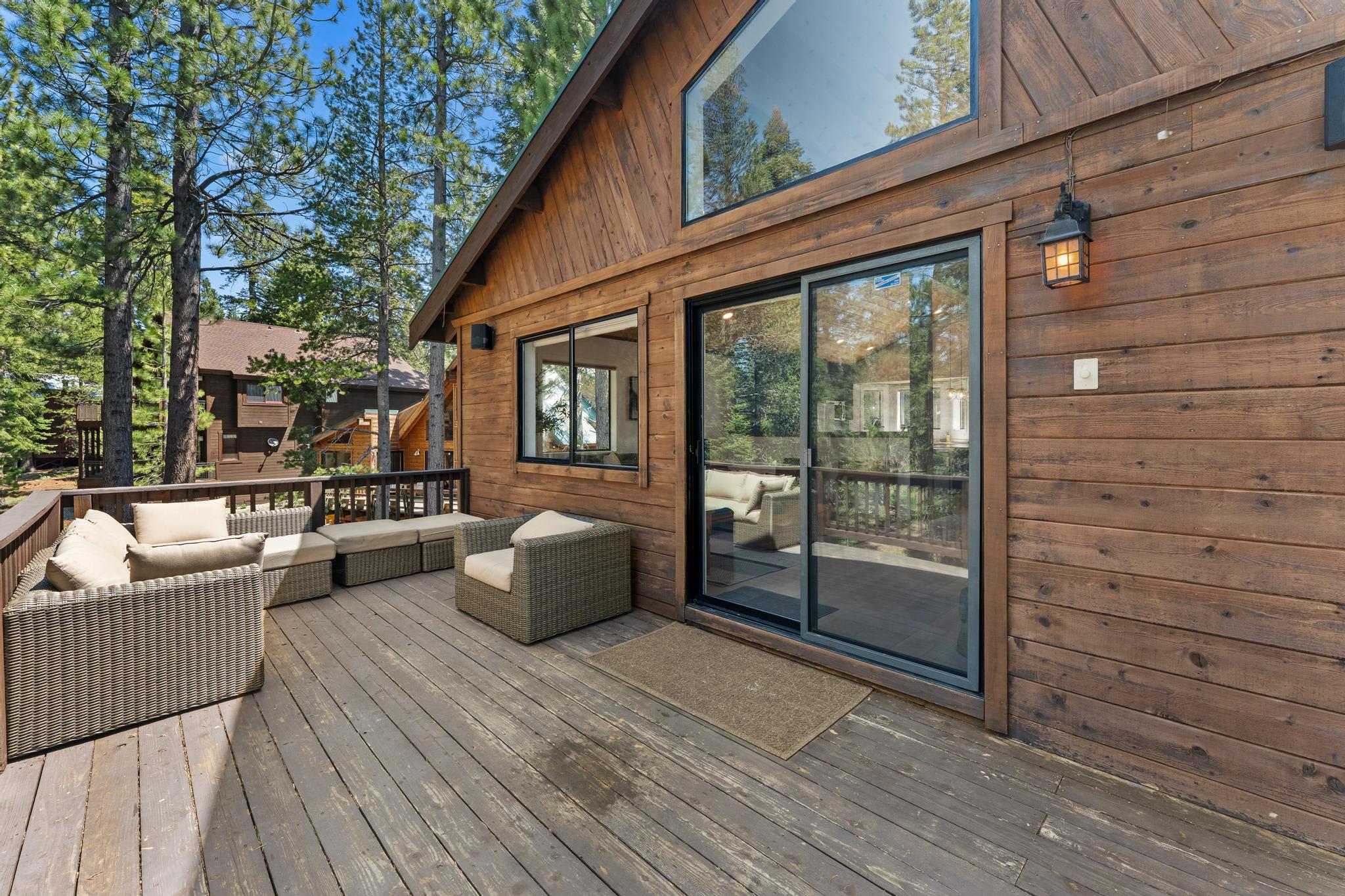 Wooden deck with outdoor seating at a Truckee vacation rental, surrounded by tall pine trees.
