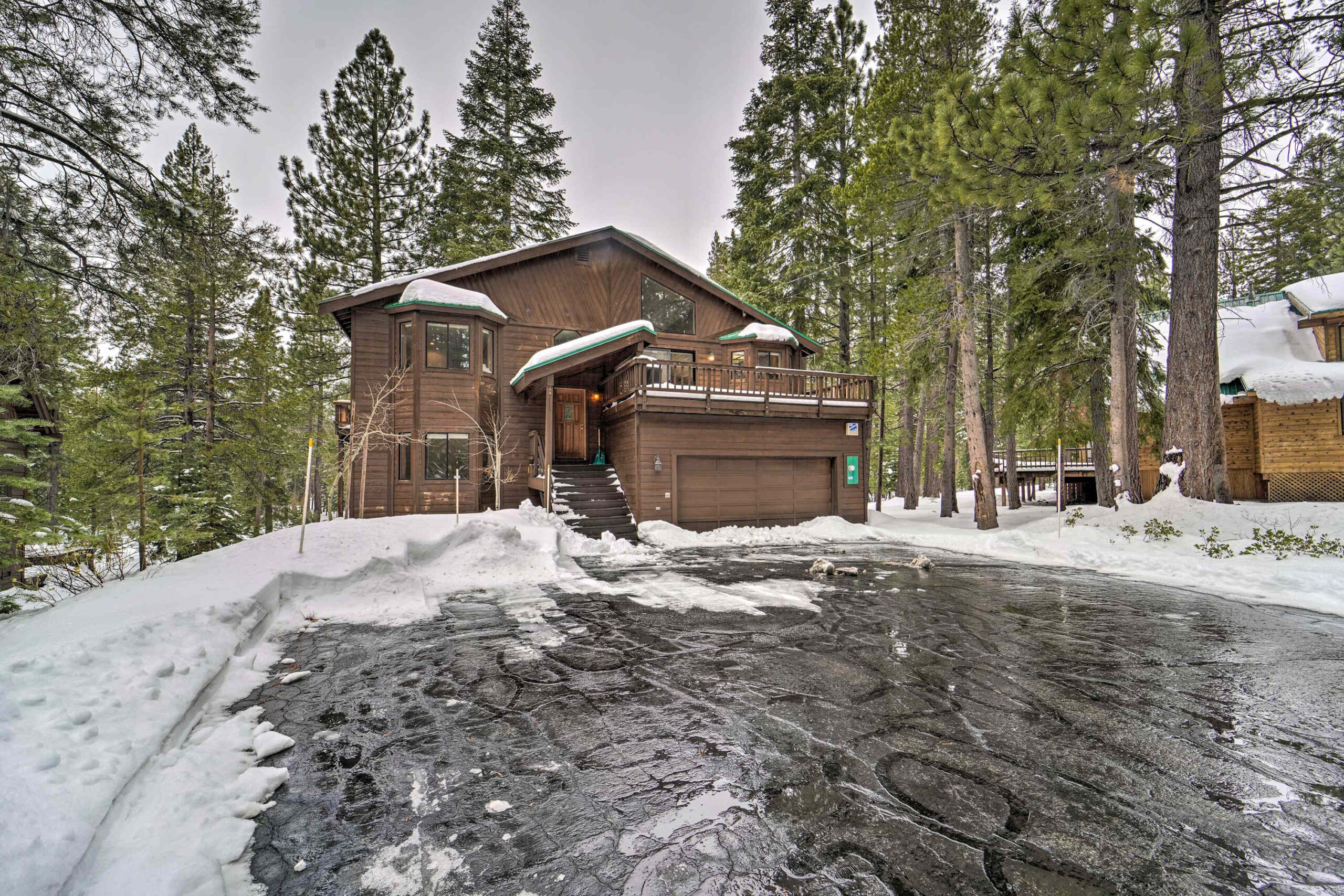 Snow-covered vacation rental cabin in Truckee surrounded by tall pine trees.