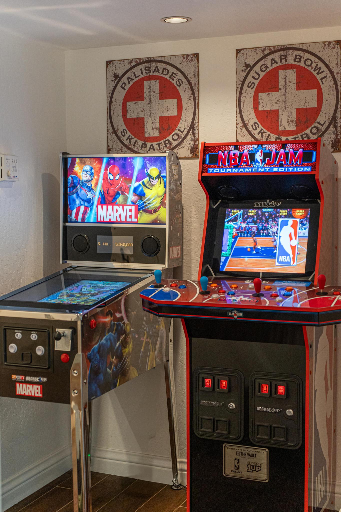 Arcade games in a Truckee vacation rental with Marvel and NBA Jam machines under ski patrol signs.