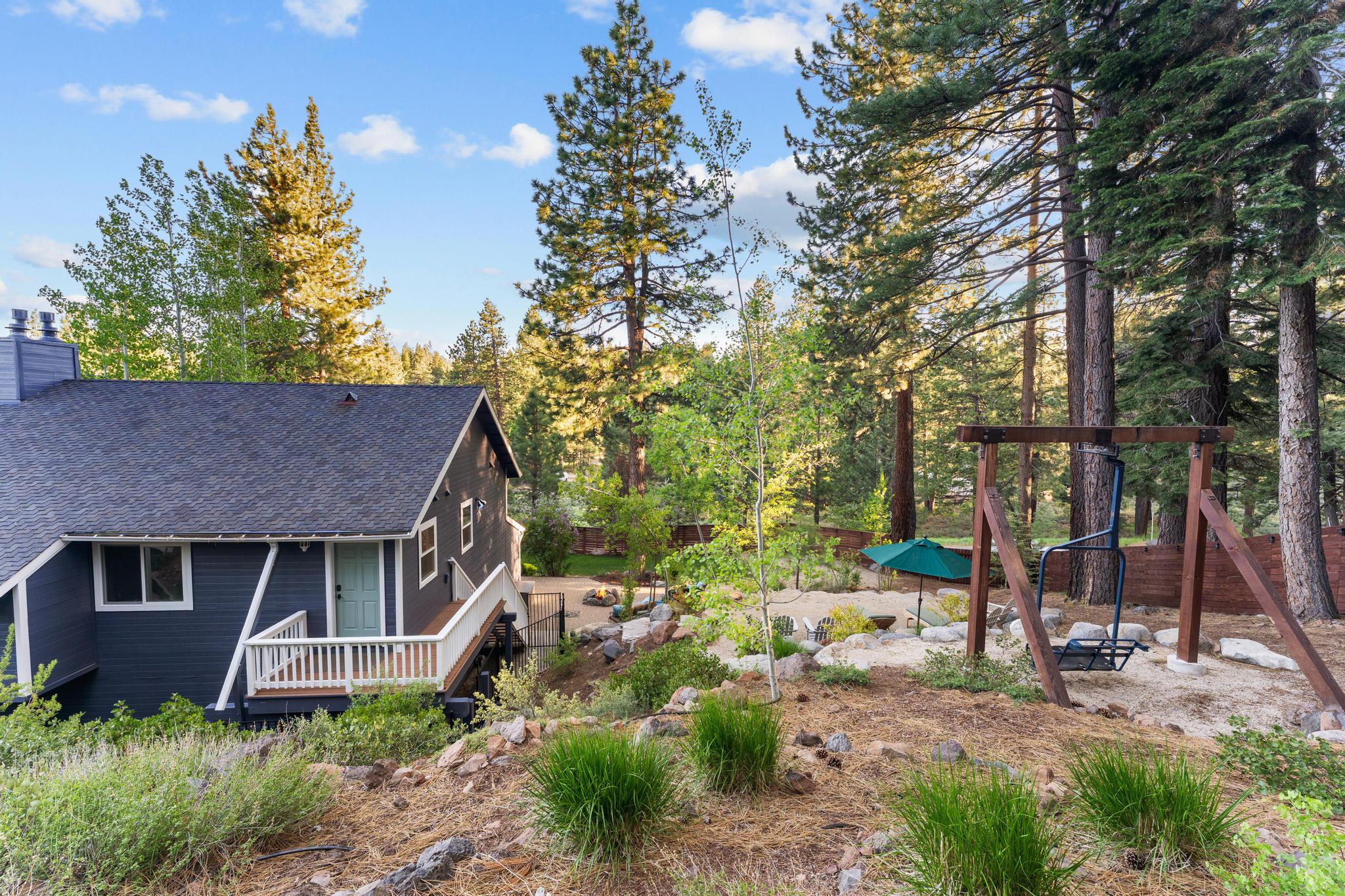 Cabin in Truckee surrounded by tall trees, a swing, and outdoor seating area, ideal for a vacation rental escape.