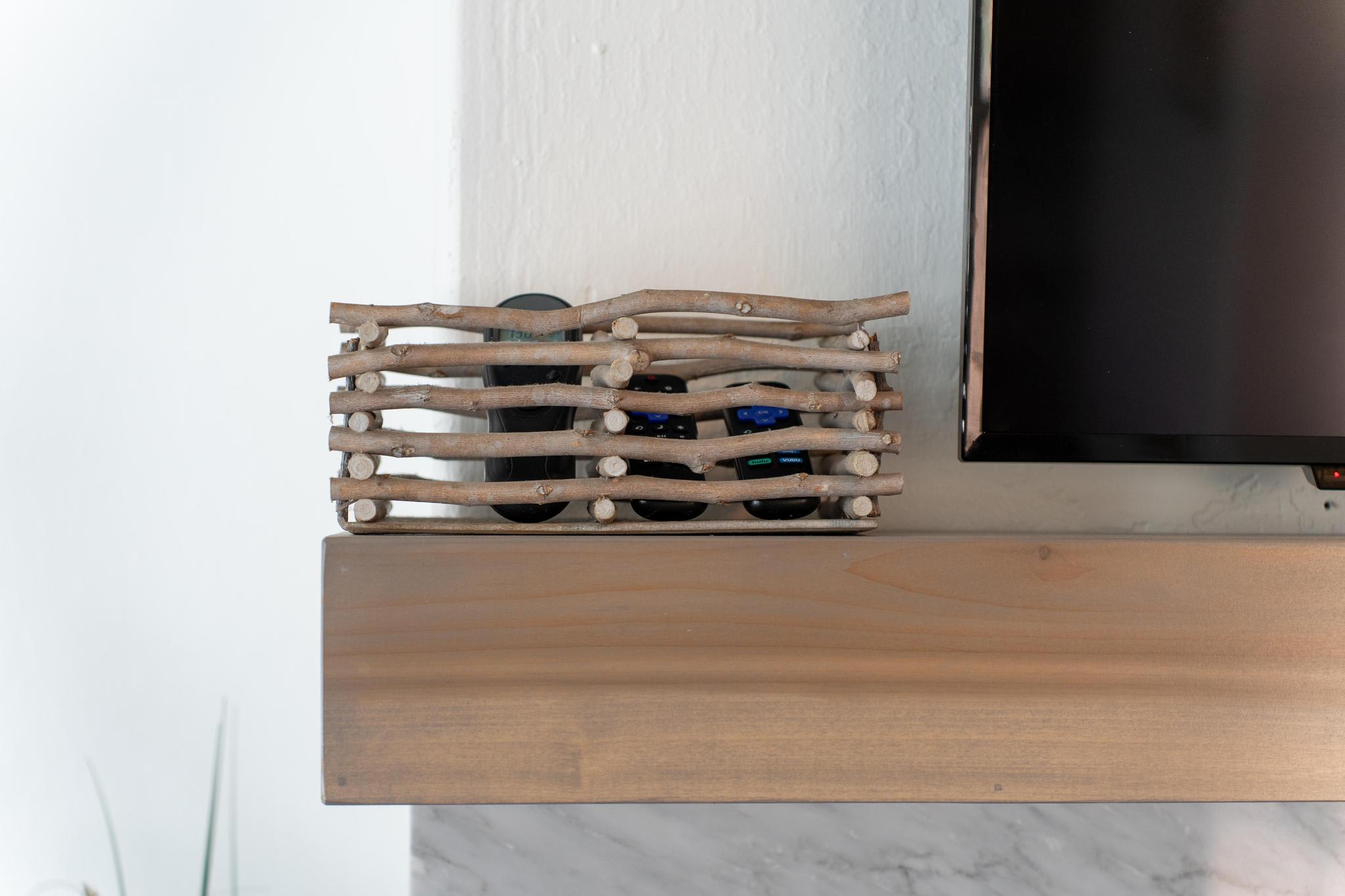 Wooden mantel in a Truckee vacation rental with a stick basket holding remote controls, adjacent to a flat-screen TV.