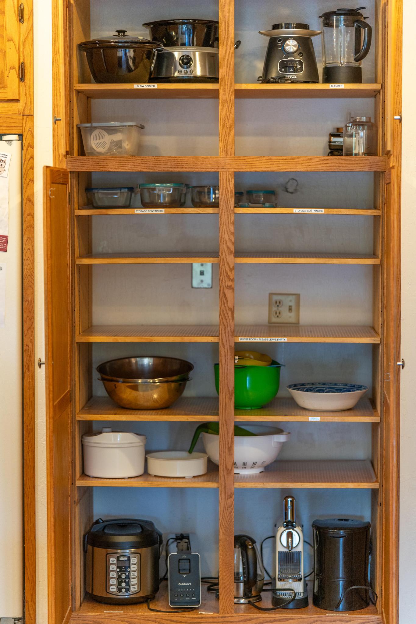 Open kitchen cabinet in Tahoe Vista vacation rental, stocked with appliances and cookware.