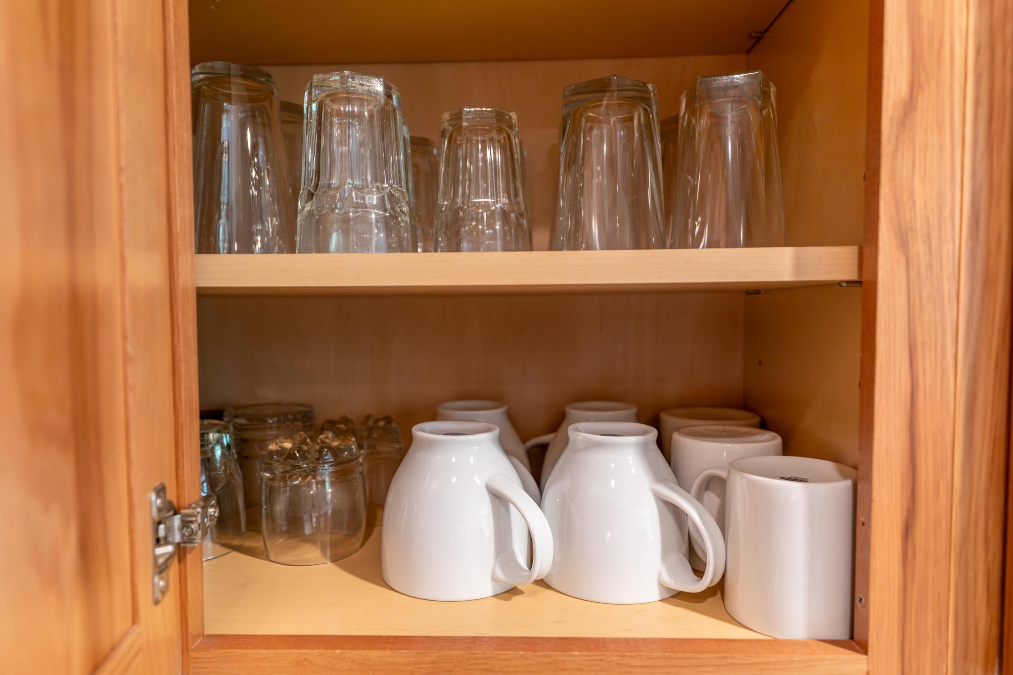 Open wooden cabinet in Truckee vacation rental with neatly stacked glassware and mugs.