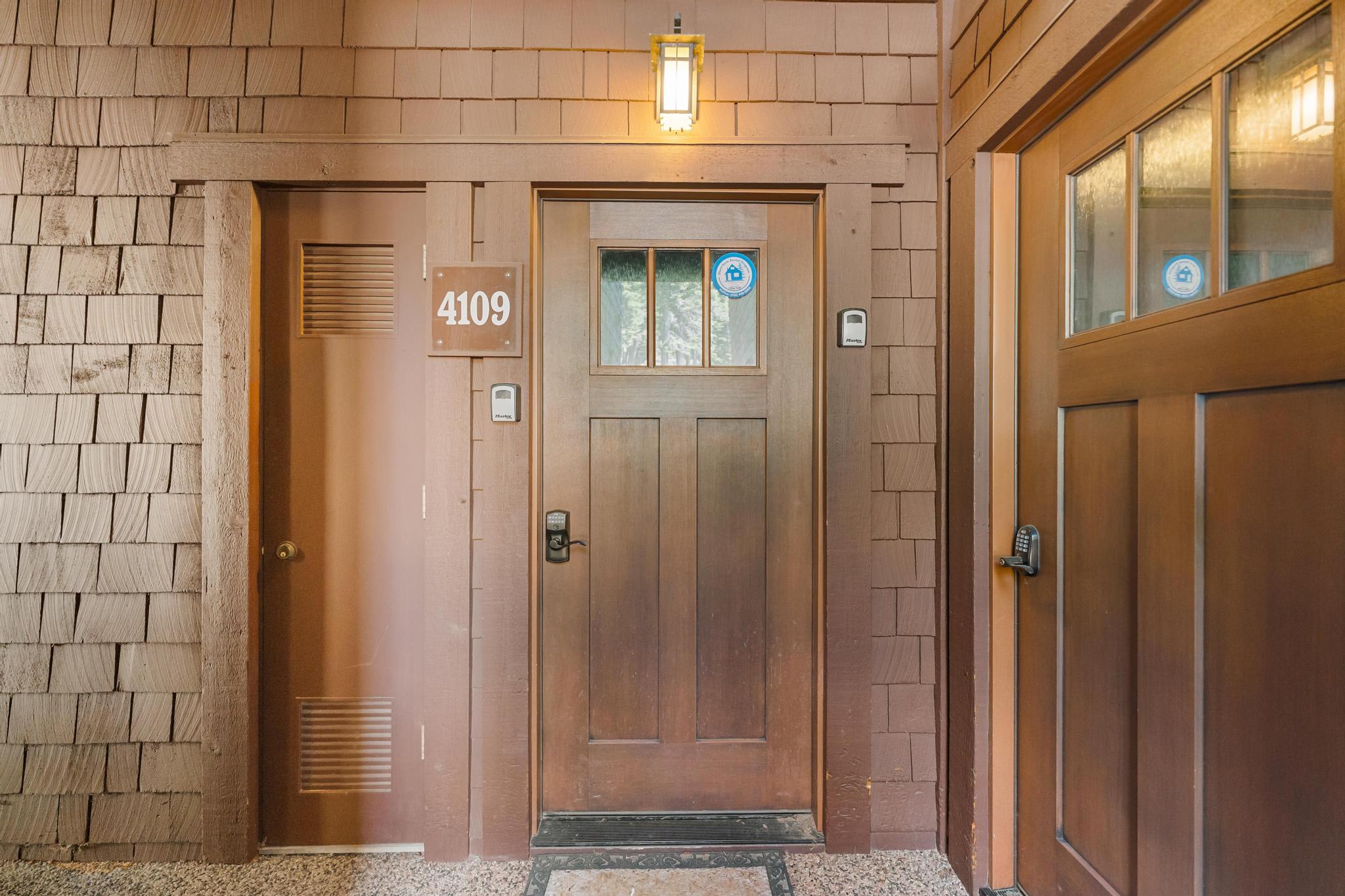 Entrance of a cozy Truckee vacation rental with a warm wooden door and address number 4109, lit by a hanging lamp.