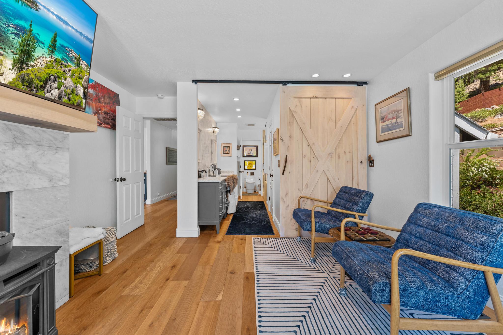 Cozy Truckee vacation rental featuring modern decor with blue chairs, a barn door, and a fireplace in the living room.