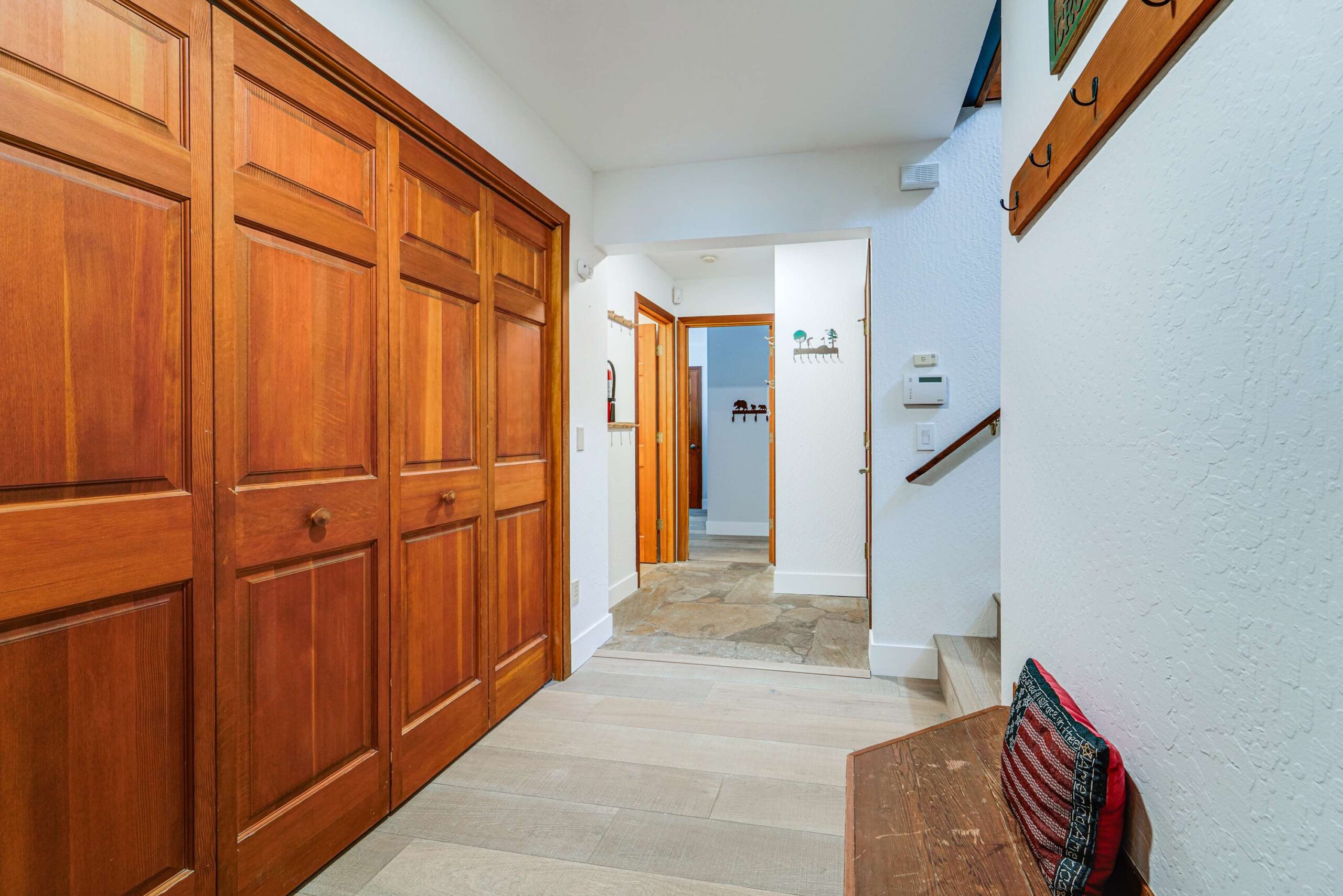 Hallway in a Truckee vacation rental with wooden closets, a bench, and stairs leading to the second floor.