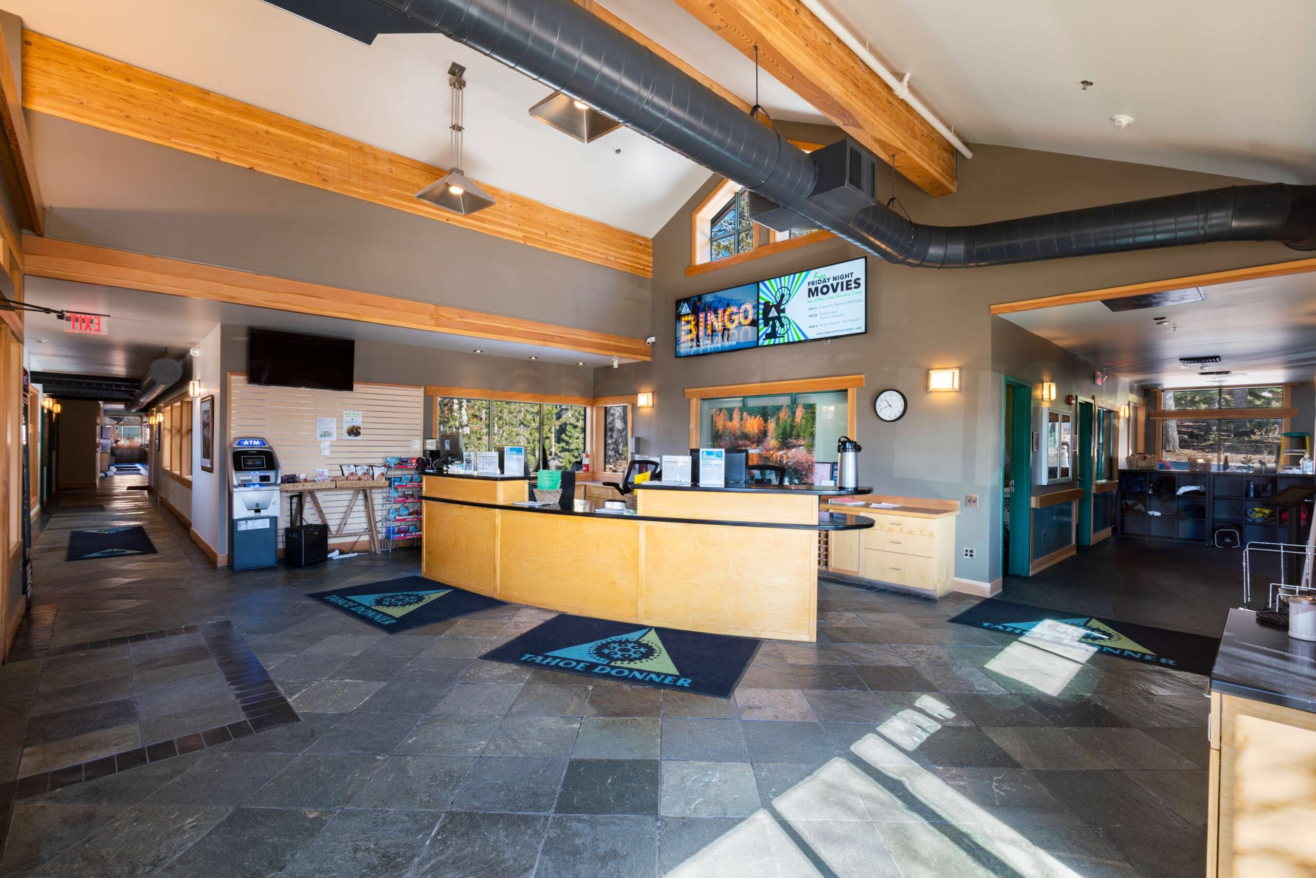 Lobby of a vacation rental in Truckee with a modern design, reception desk, promotional signs, and natural light.
