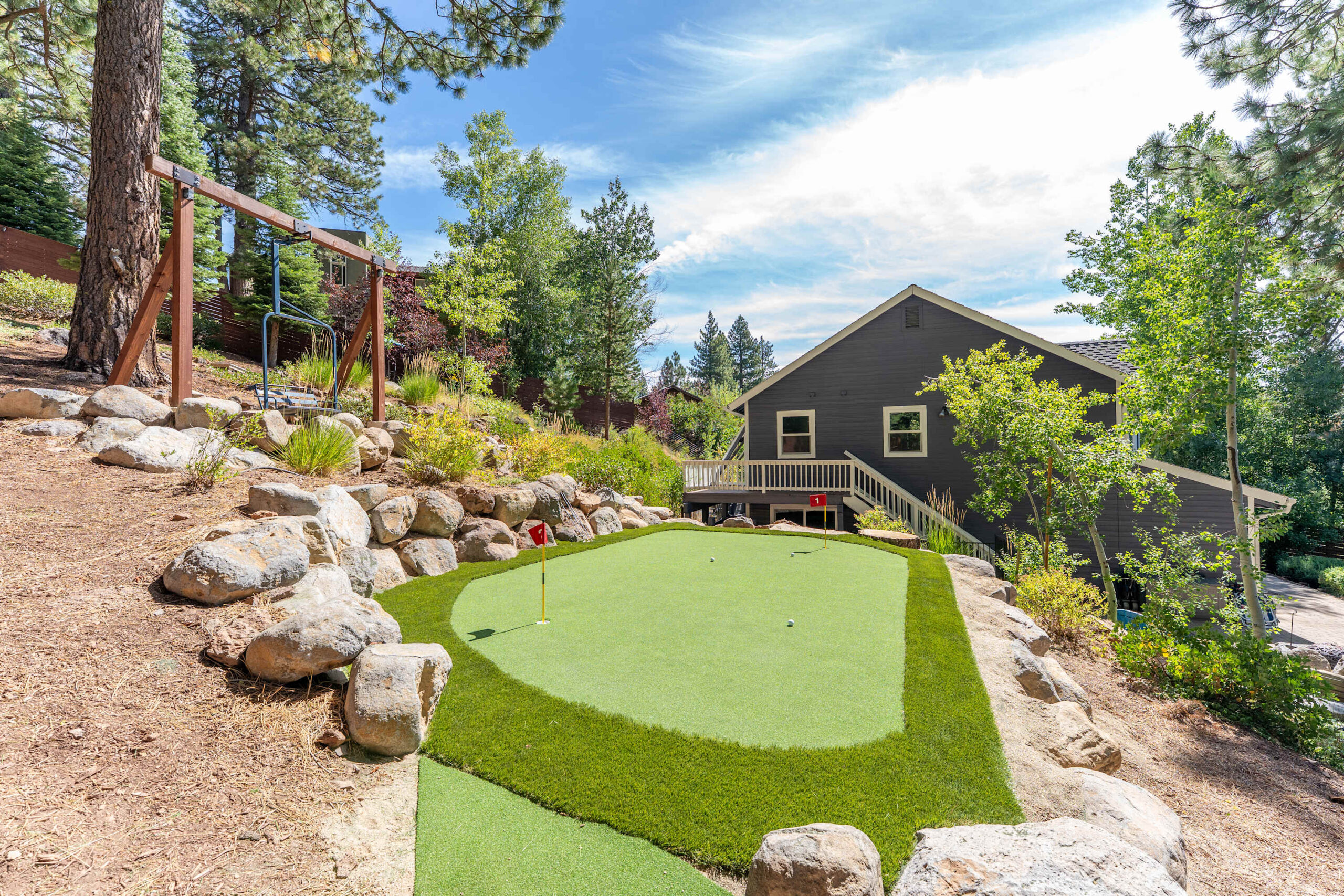 Vacation rental in Truckee with a mini-golf putting green, surrounded by trees and a charming house in the background.