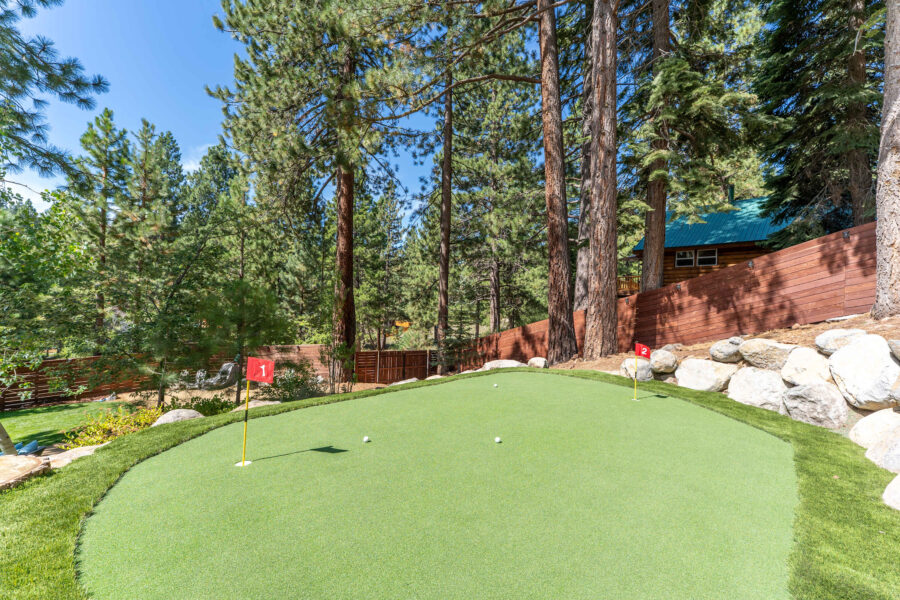 Miniature putting green in a wooded backyard at a Truckee vacation rental, surrounded by tall pine trees.