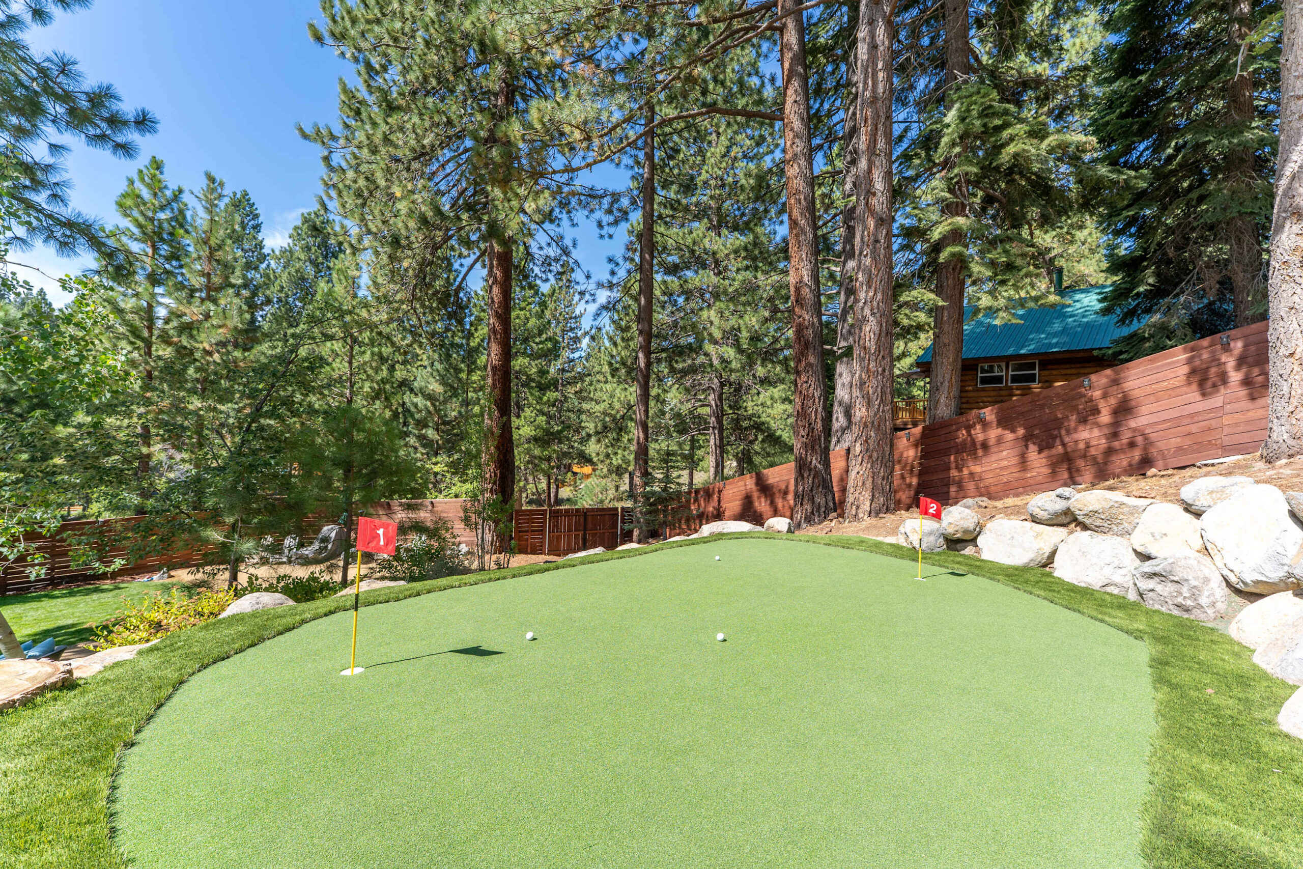 Miniature putting green in a wooded backyard at a Truckee vacation rental, surrounded by tall pine trees.