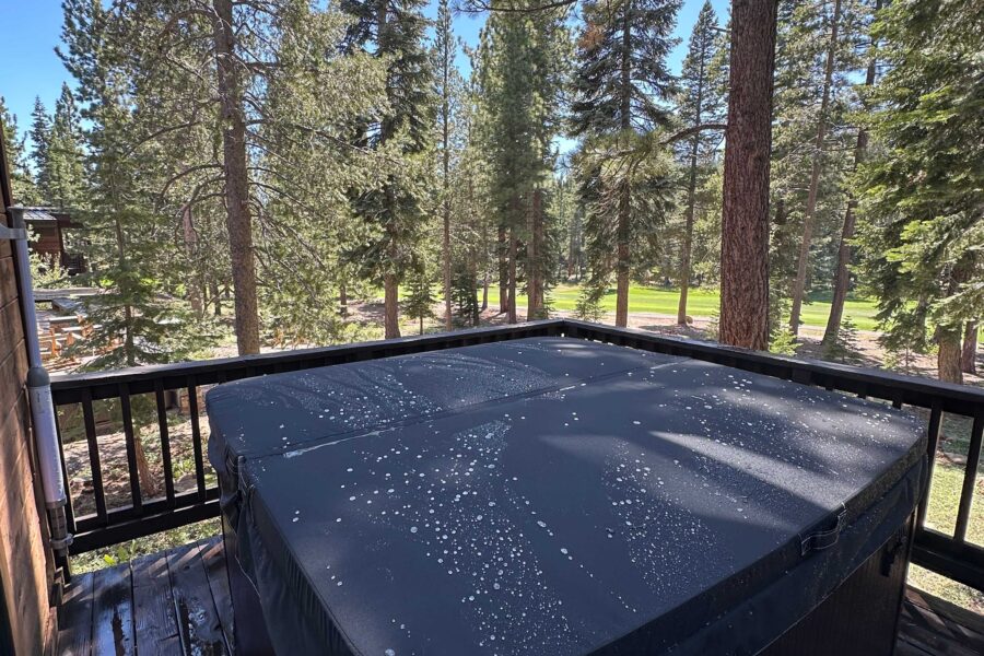 Hot tub on the deck of a vacation rental in Truckee, surrounded by tall pine trees and a sunny forest view.