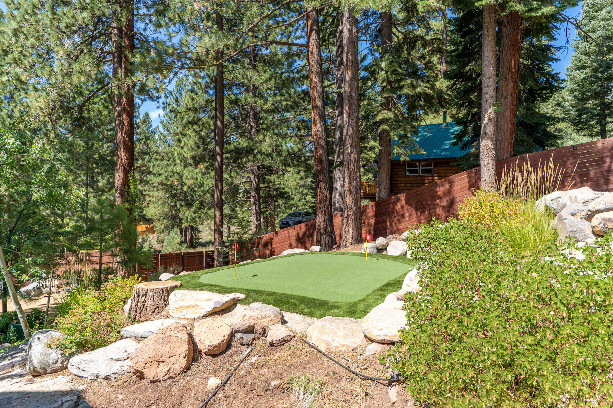 Mini golf course nestled in forest setting at a Truckee vacation rental, surrounded by tall trees and natural landscape.