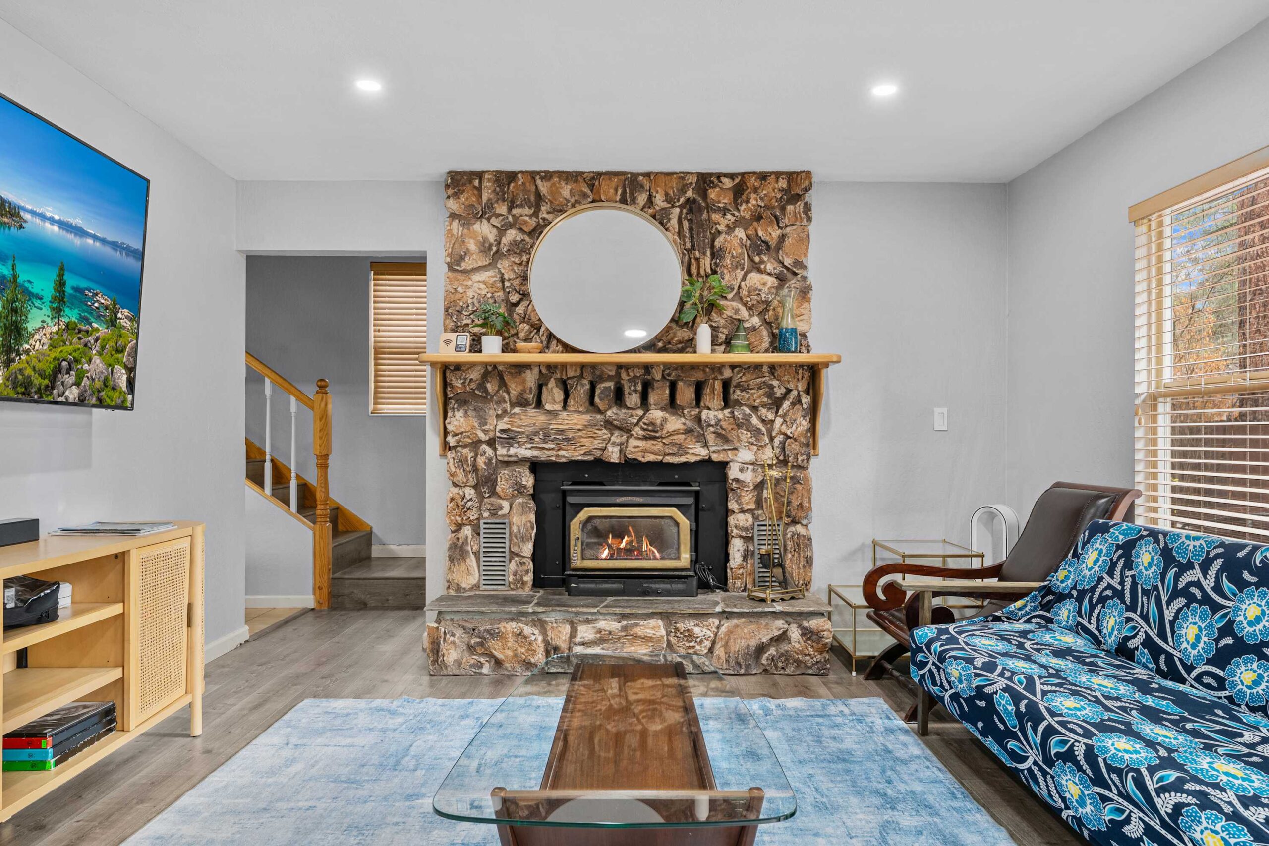 Cozy Truckee vacation rental living room with stone fireplace, patterned sofa, and large TV.