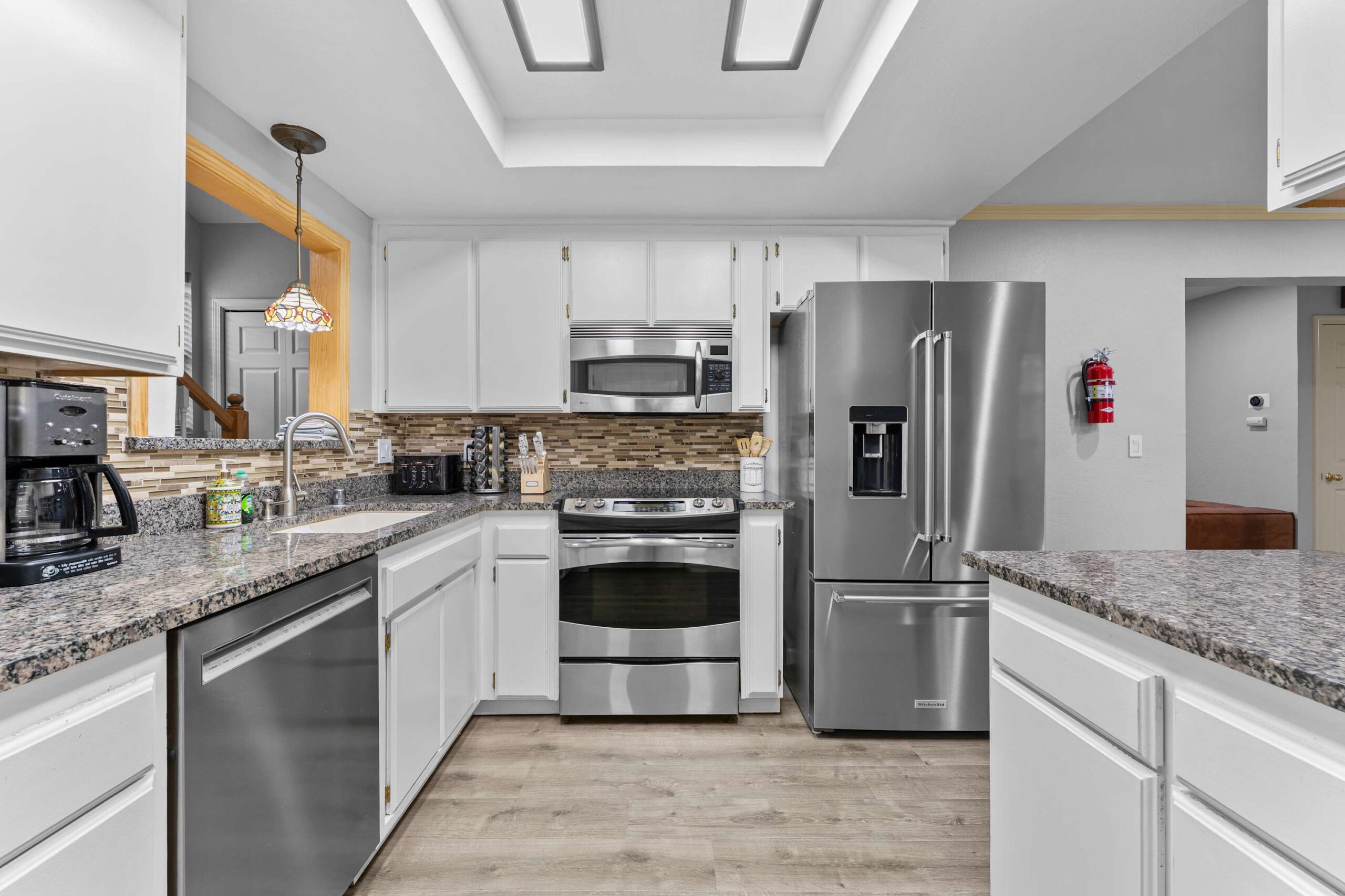 Modern kitchen in a Truckee vacation rental, featuring granite countertops, stainless steel appliances, and white cabinets.