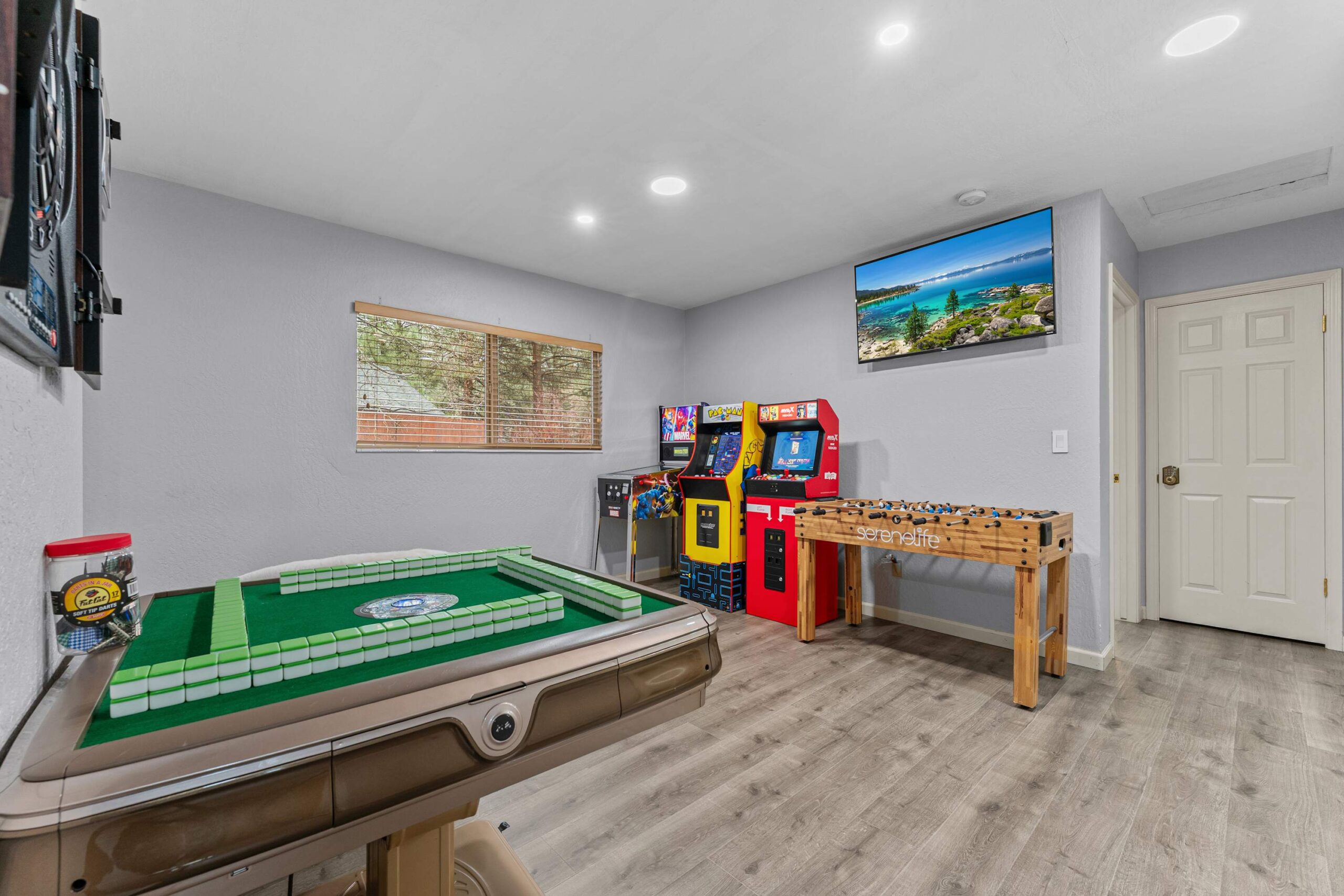 Game room in Truckee vacation rental with arcade machines, foosball table, and large window.