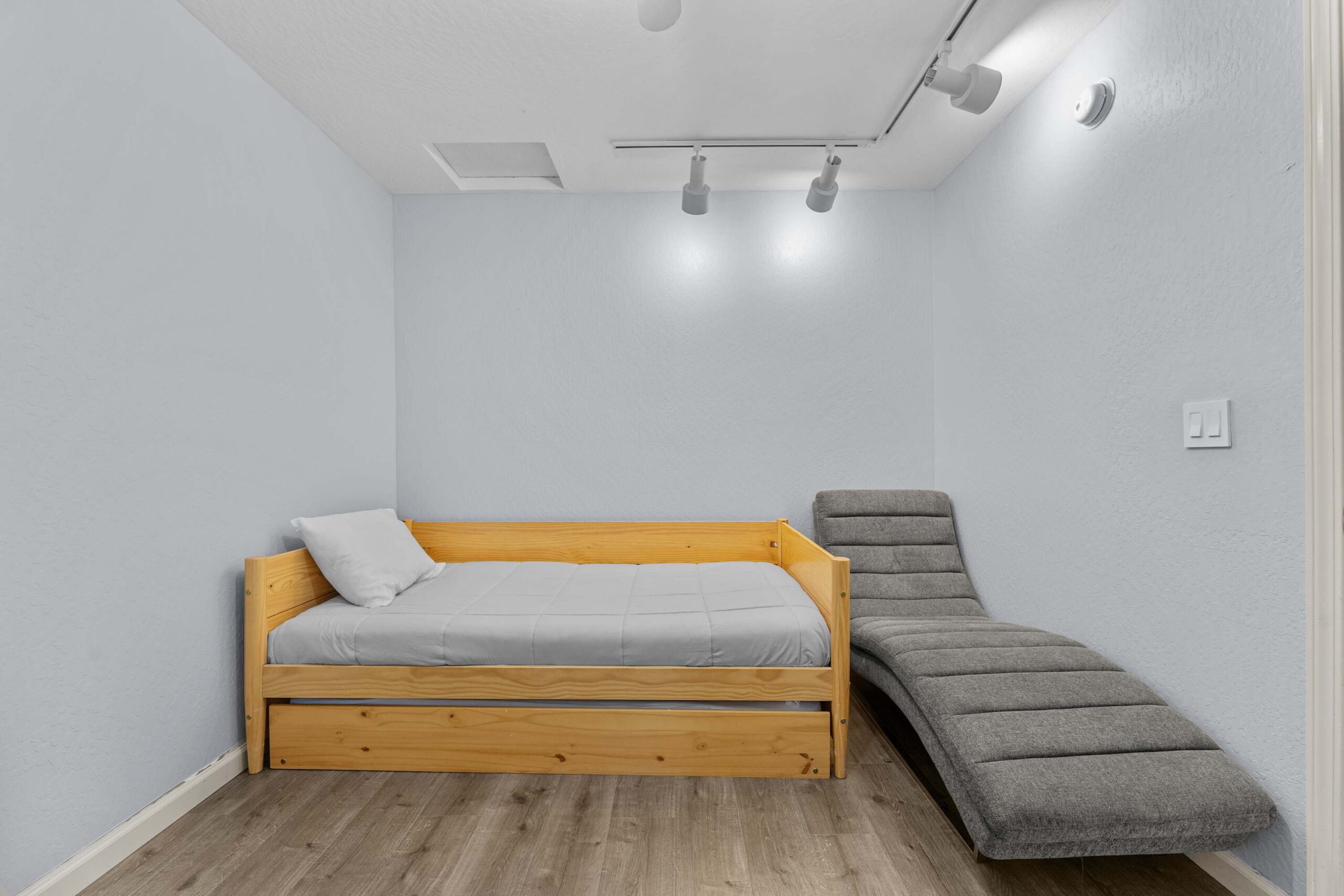 Wooden daybed and gray chaise lounge in a minimalist Truckee vacation rental room.