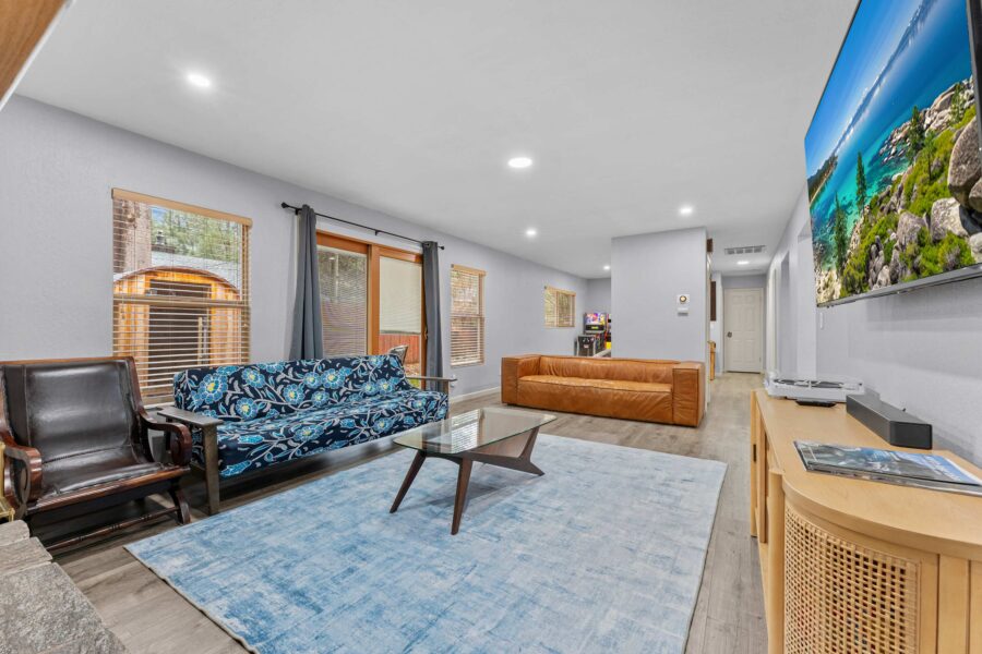 Spacious living room in a Truckee vacation rental, with colorful sofa, leather chair, glass table, and large TV screen.