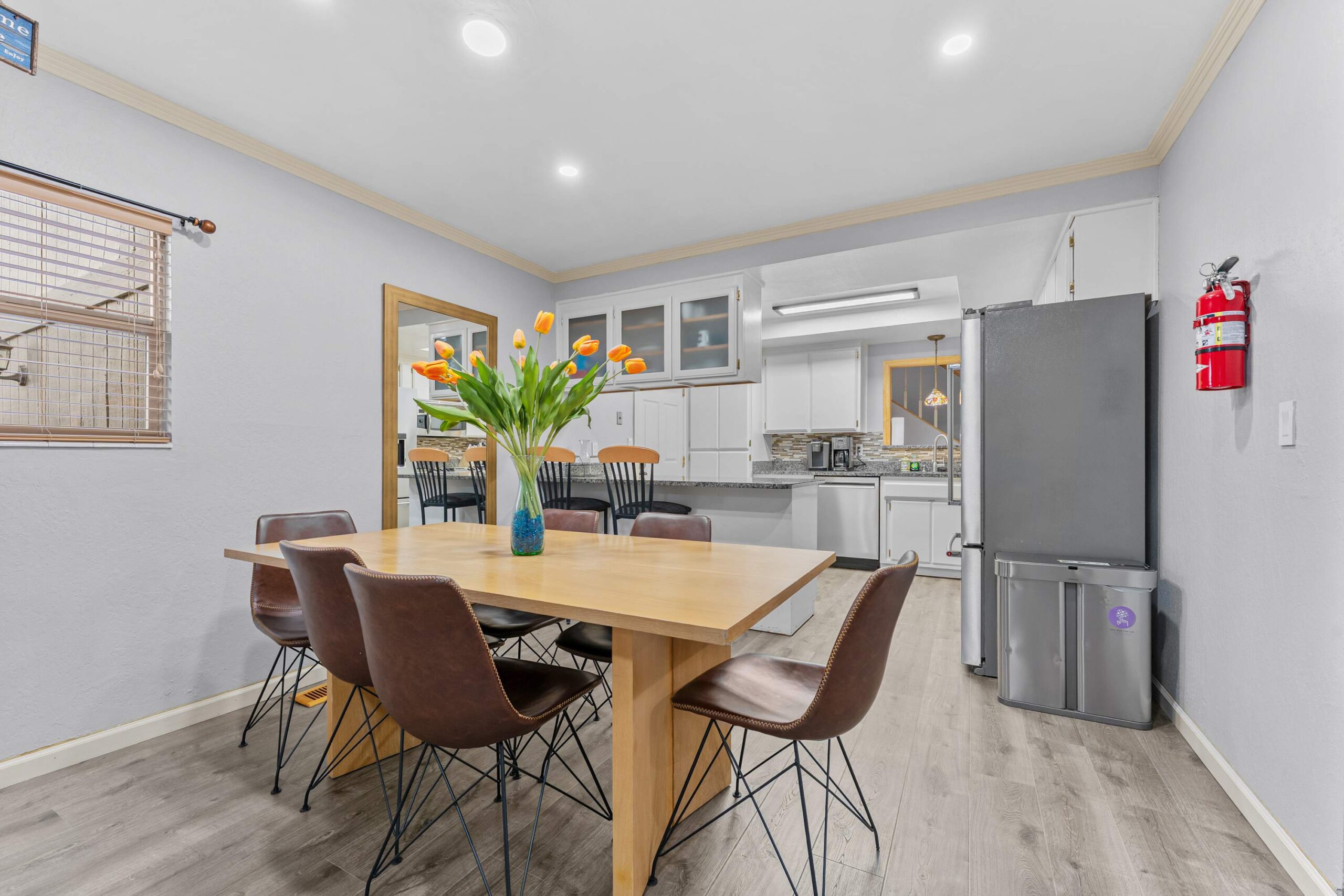 Dining area in a Truckee vacation rental, featuring a wooden table, brown chairs, and tulips in a vase.