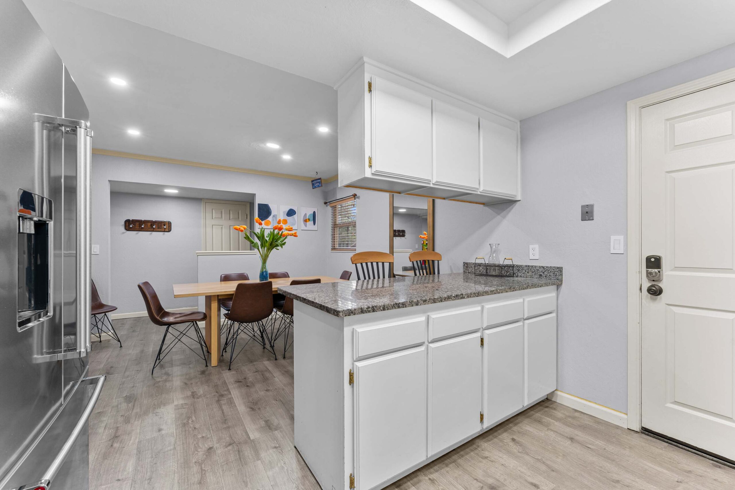 Modern kitchen and dining area in a Truckee vacation rental with white cabinets, granite countertops, and a wooden table.