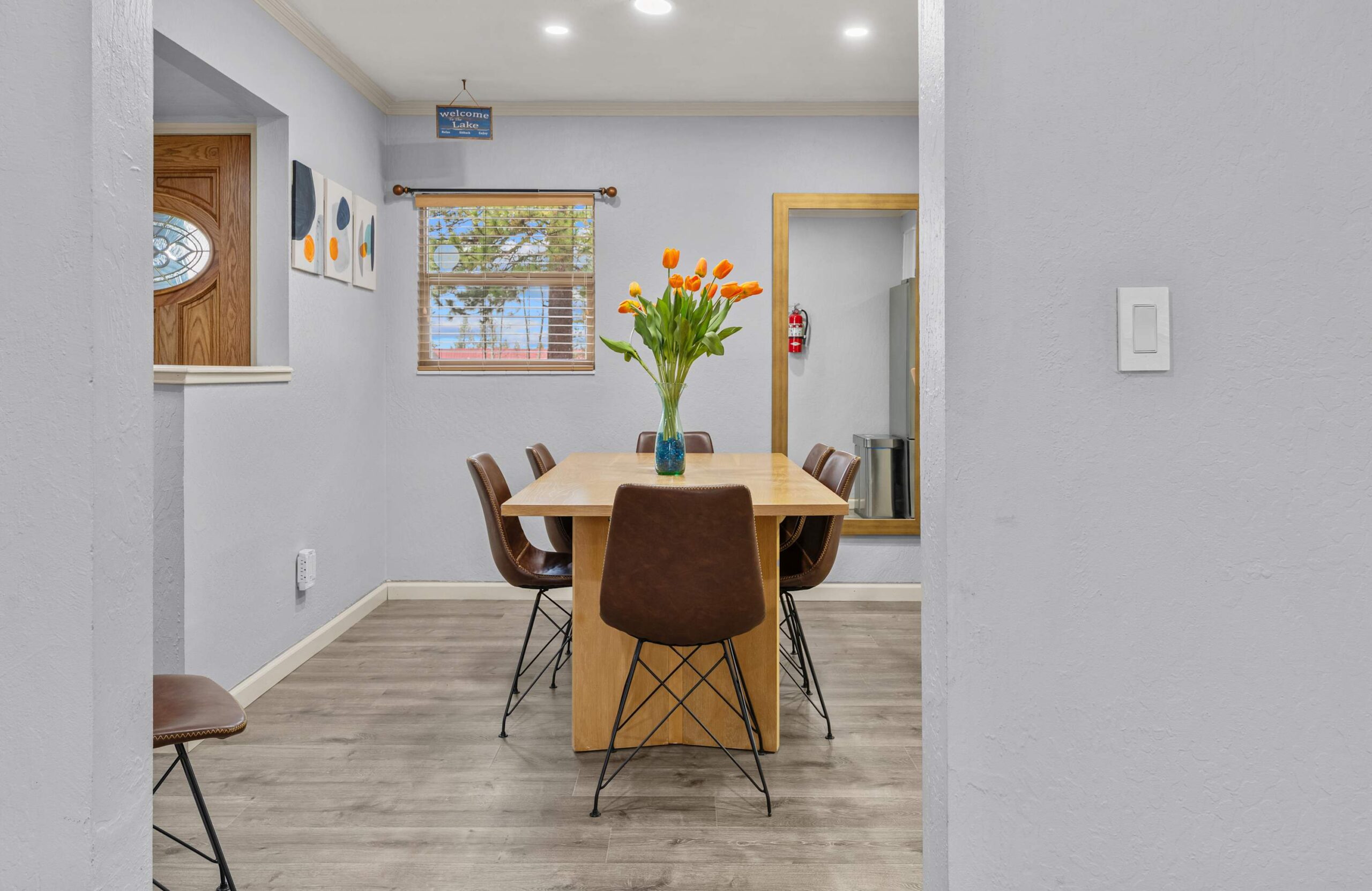Dining area in Truckee vacation rental with a wooden table, brown chairs, and a vase of orange tulips.