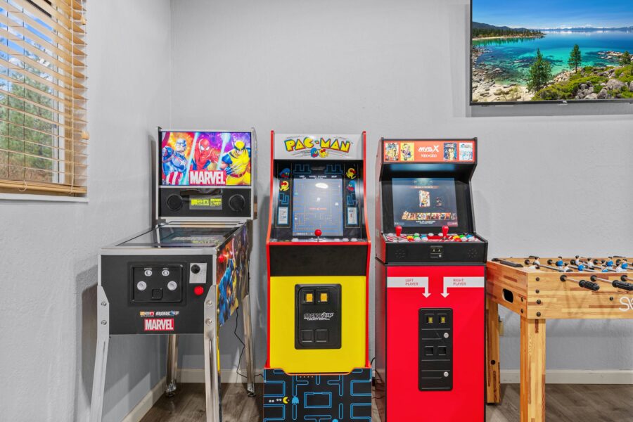 Game room in a Truckee vacation rental with arcade machines and a foosball table near a window.