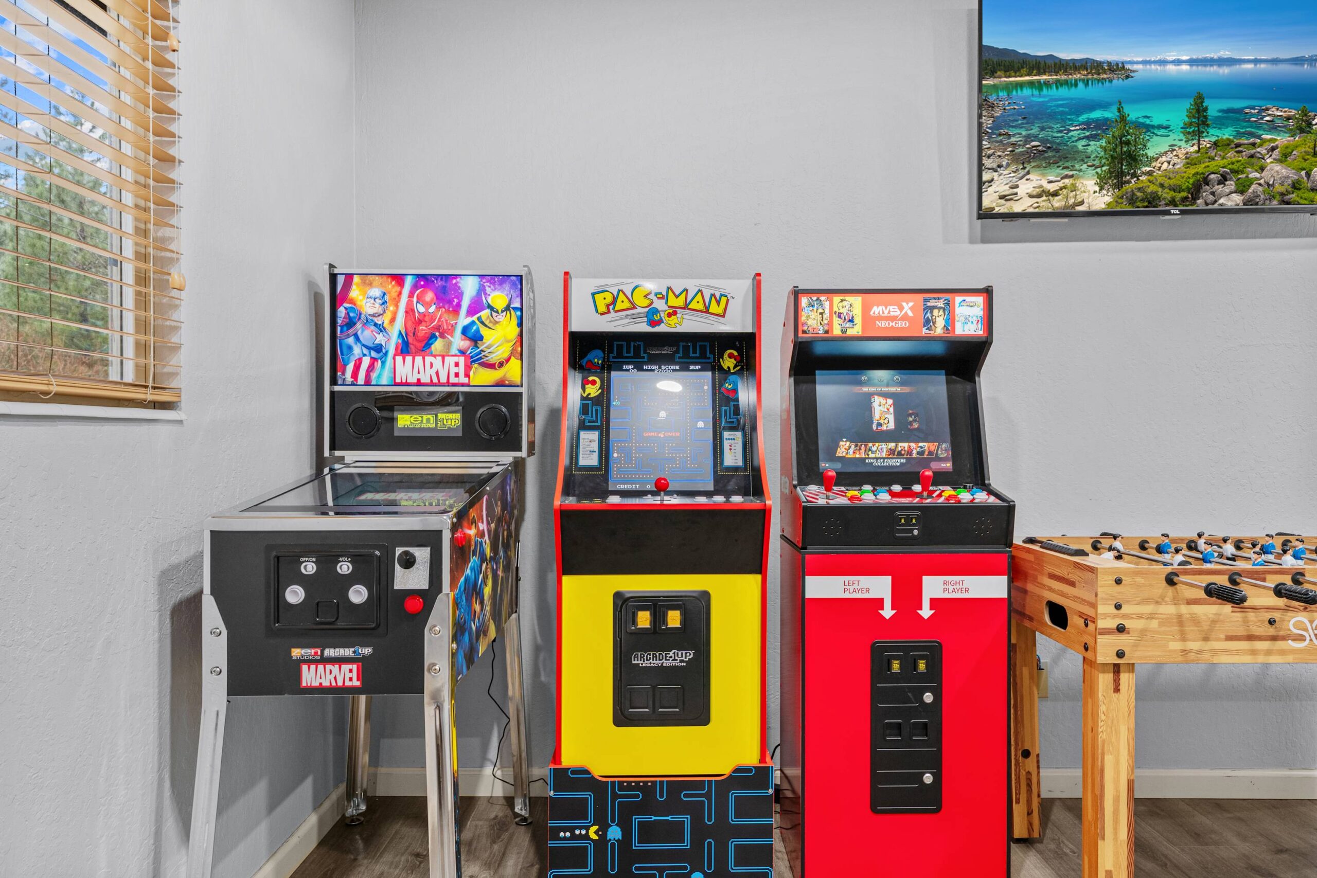 Game room in a Truckee vacation rental with arcade machines and a foosball table near a window.