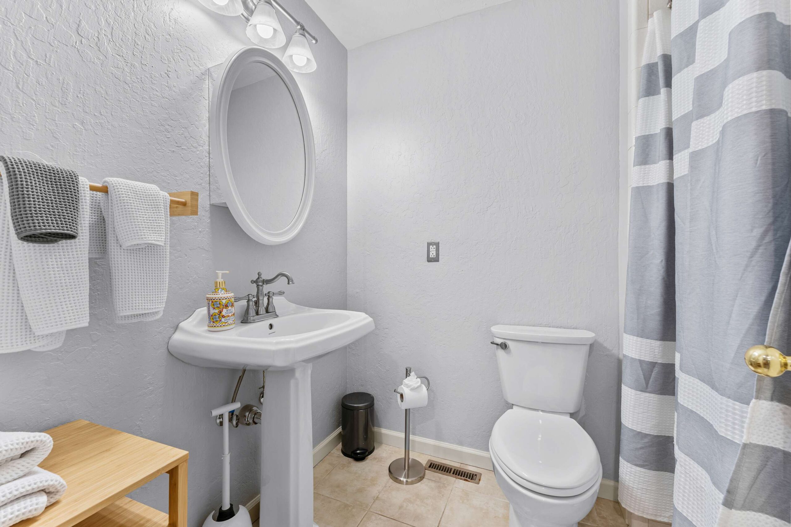 Bathroom in a Truckee vacation rental with white pedestal sink, towels, toilet, and gray-and-white shower curtain.