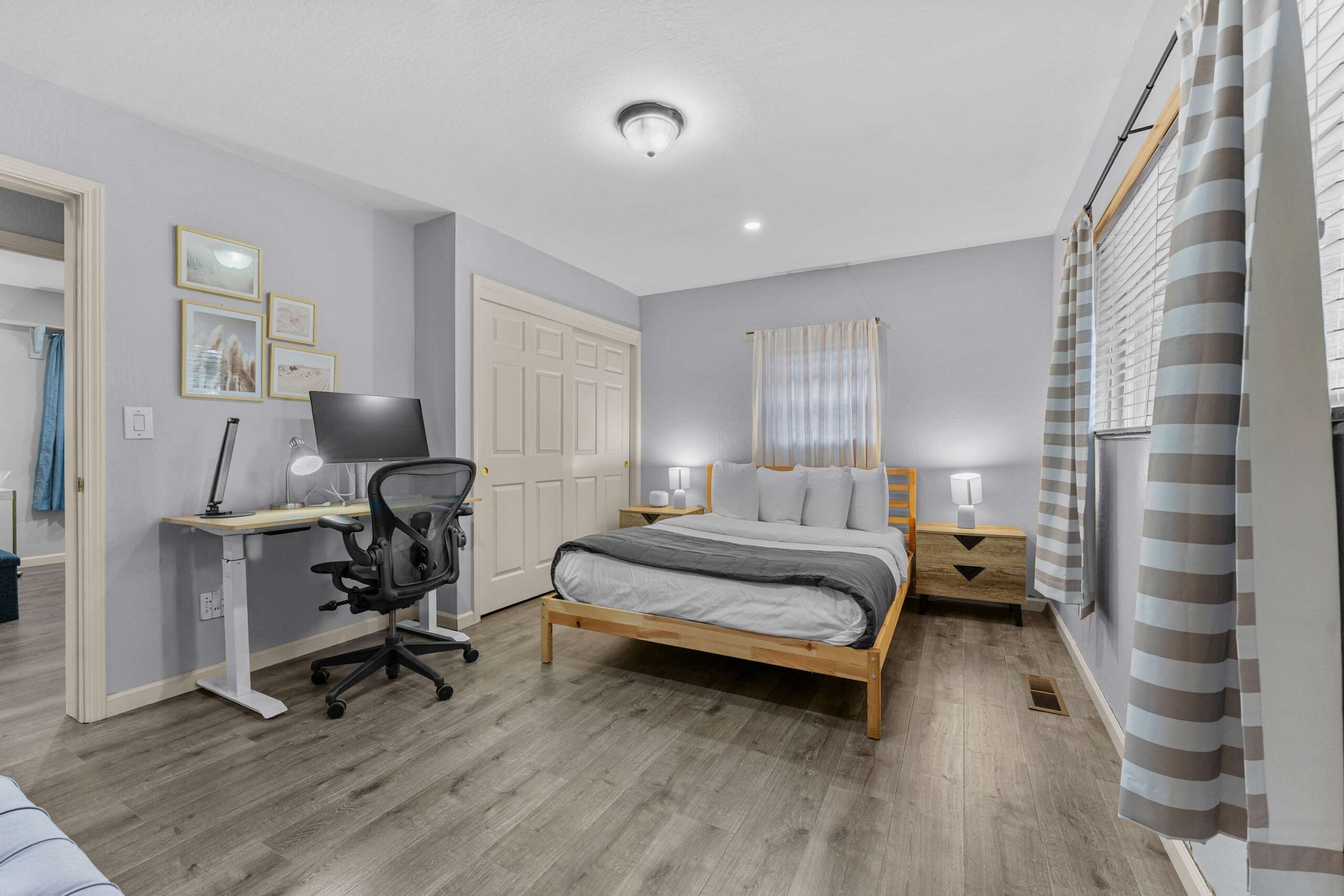 Modern bedroom in Truckee vacation rental with a cozy bed, desk, and large window with striped curtains.