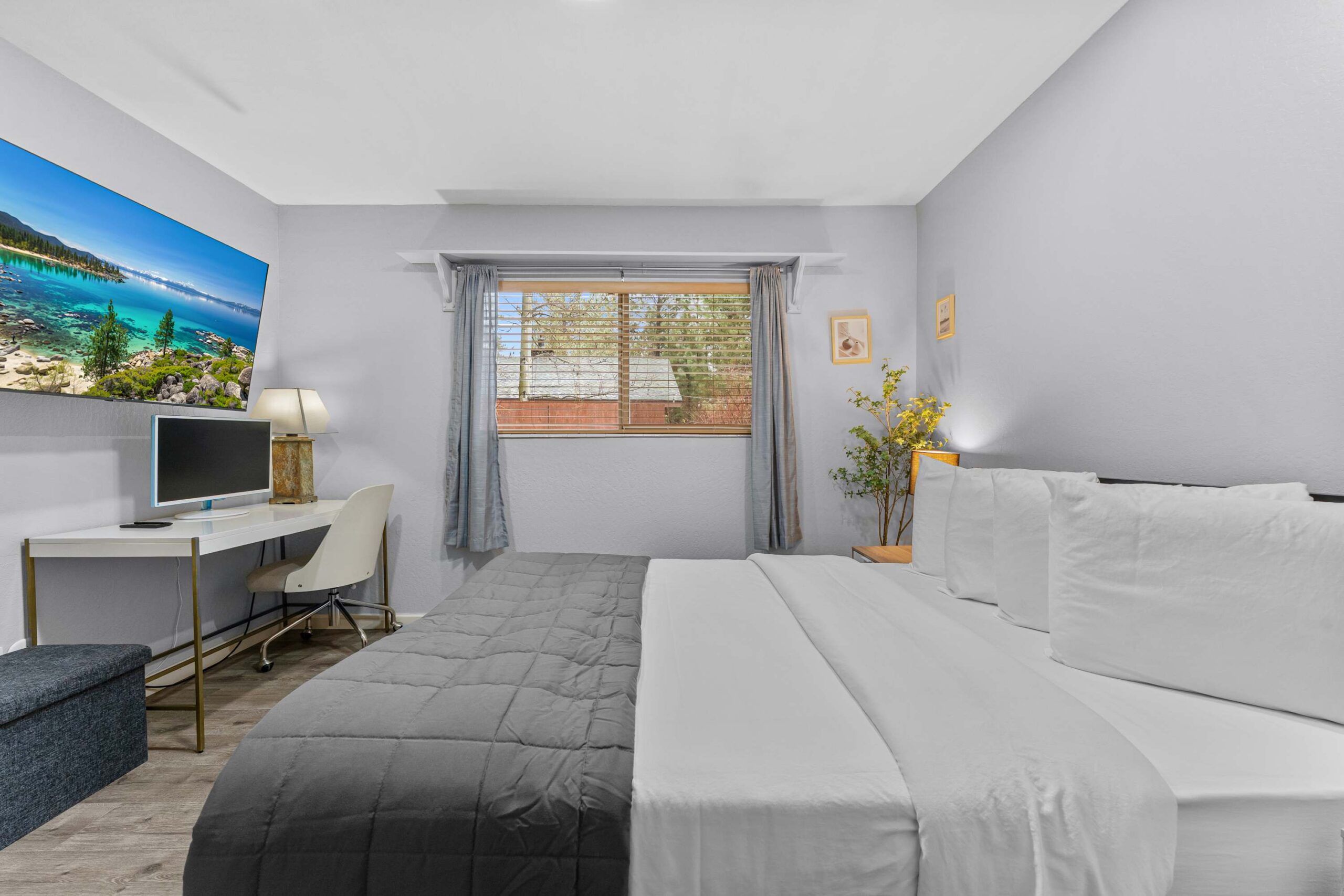 Cozy bedroom in a Truckee vacation rental, featuring a large bed, desk with chair, and wall-mounted TV.